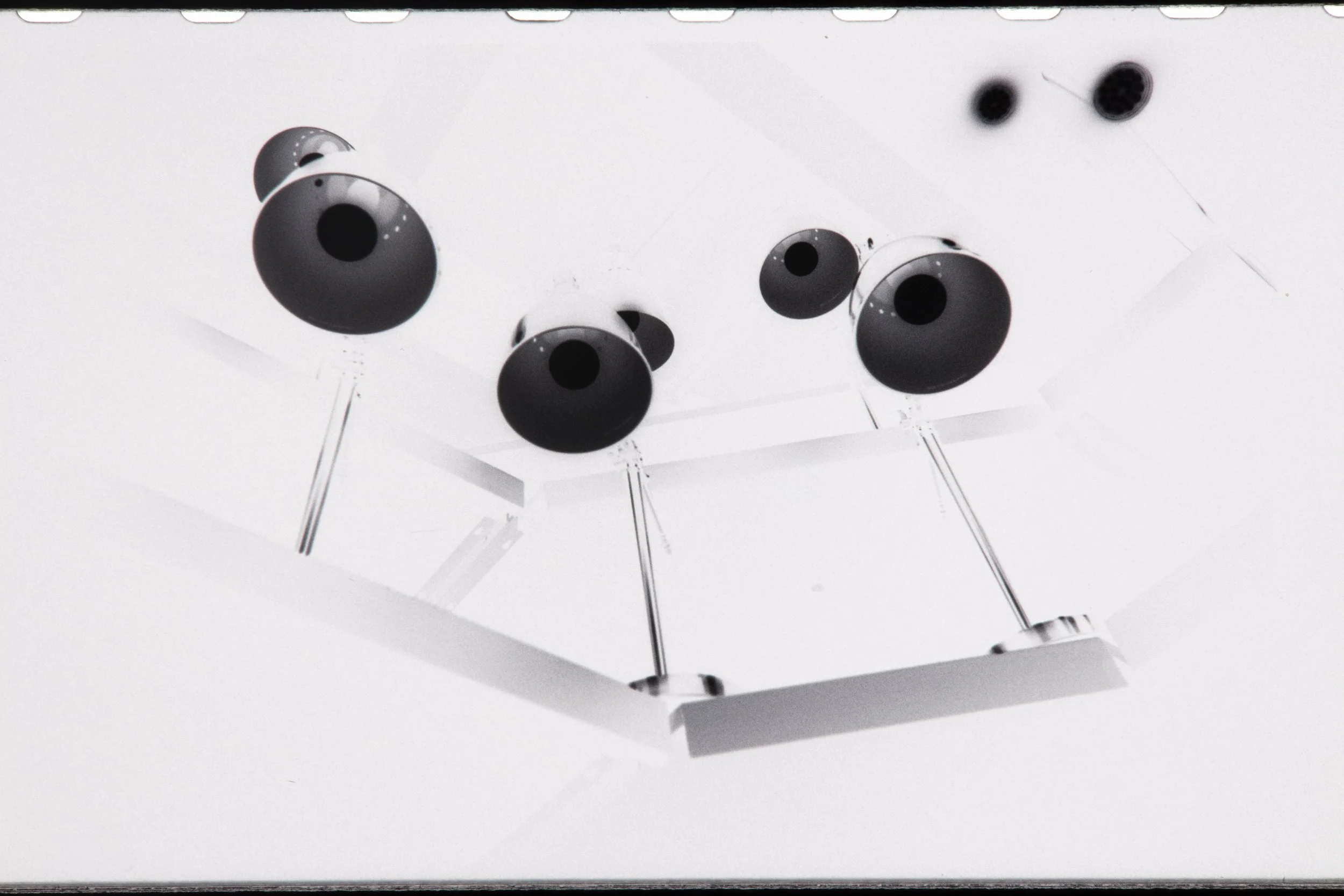 Multiple black and white spherical sensors mounted on thin metal rods on a white surface, viewed from below.