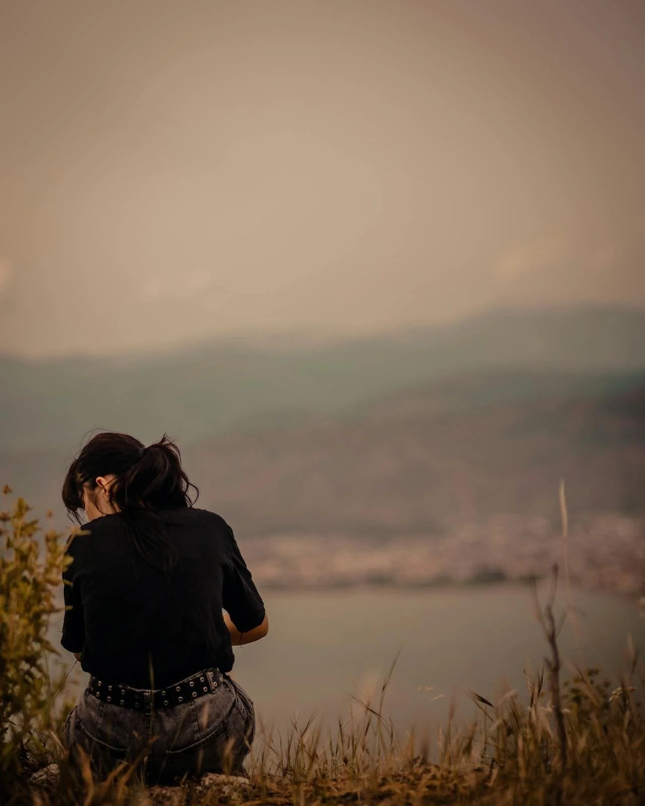 woman sitting alone overlooking a lake