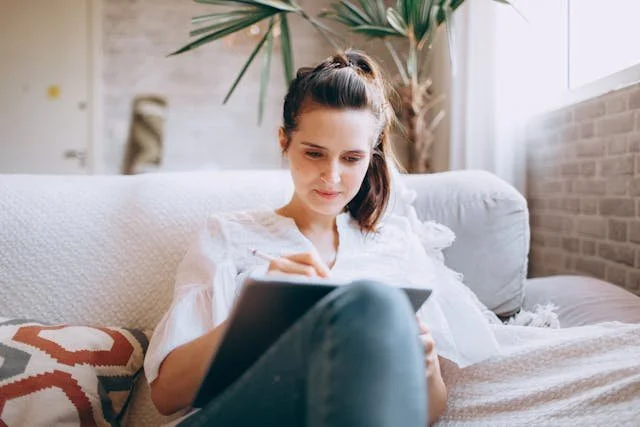 woman-sitting-on-a-sofa-and-using-a-tablet