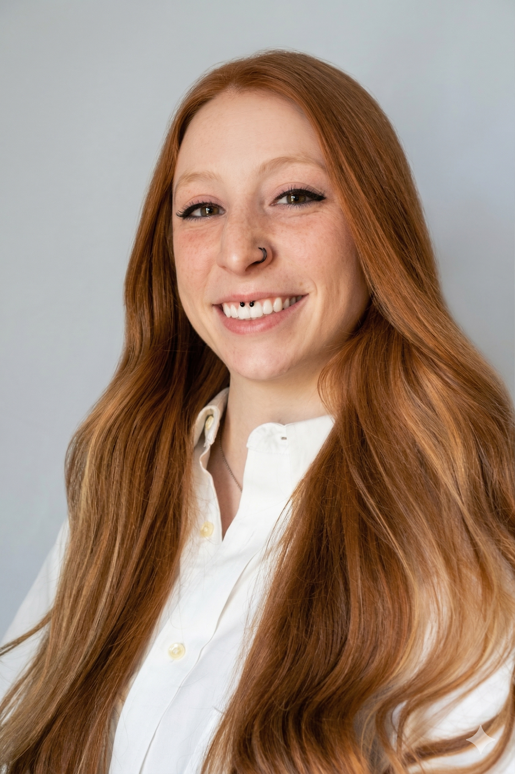 woman with auburn hair and a white shirt smiling