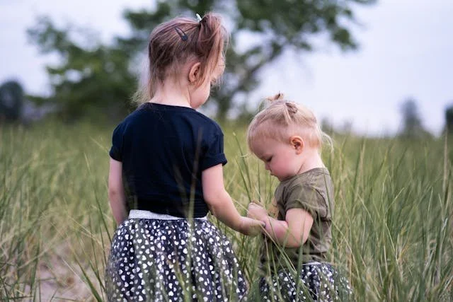 two-girls-standing-on-grass-field