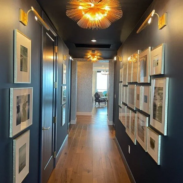Framed Memories. #interiordesign #interiordesigner #interiors #navyblue #gallerywall #woodfloors #visualcomfortlighting #condoliving #stpetersburginteriordesign #stpetersburginteriors #interiordesignstpete
