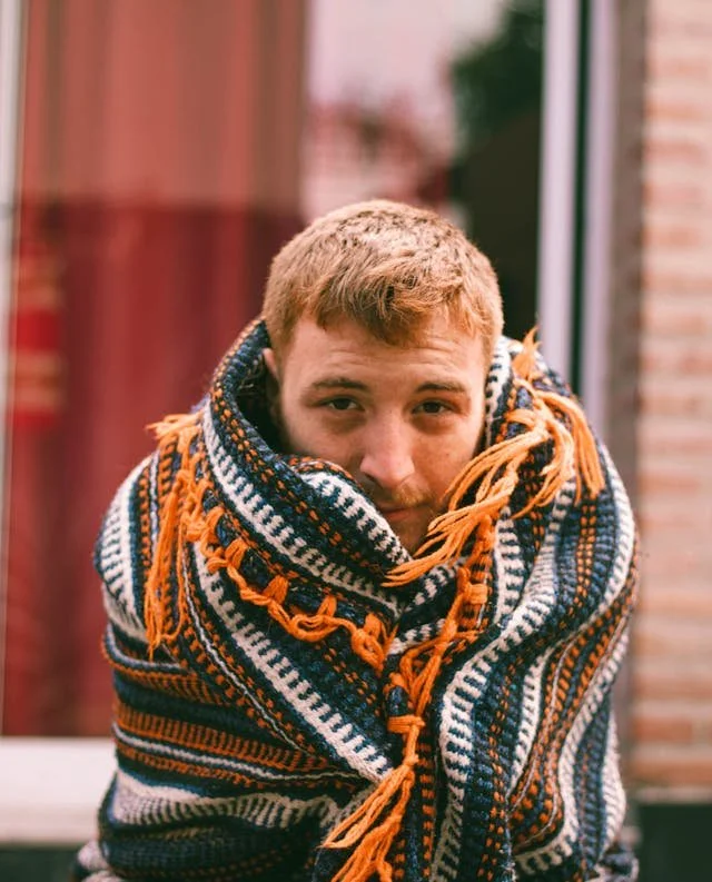 a man wrapped up in a comfy blanket