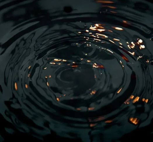 a ripple effect in a pool of water that is dark