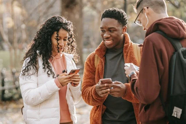 Three teens out smiling on their phones