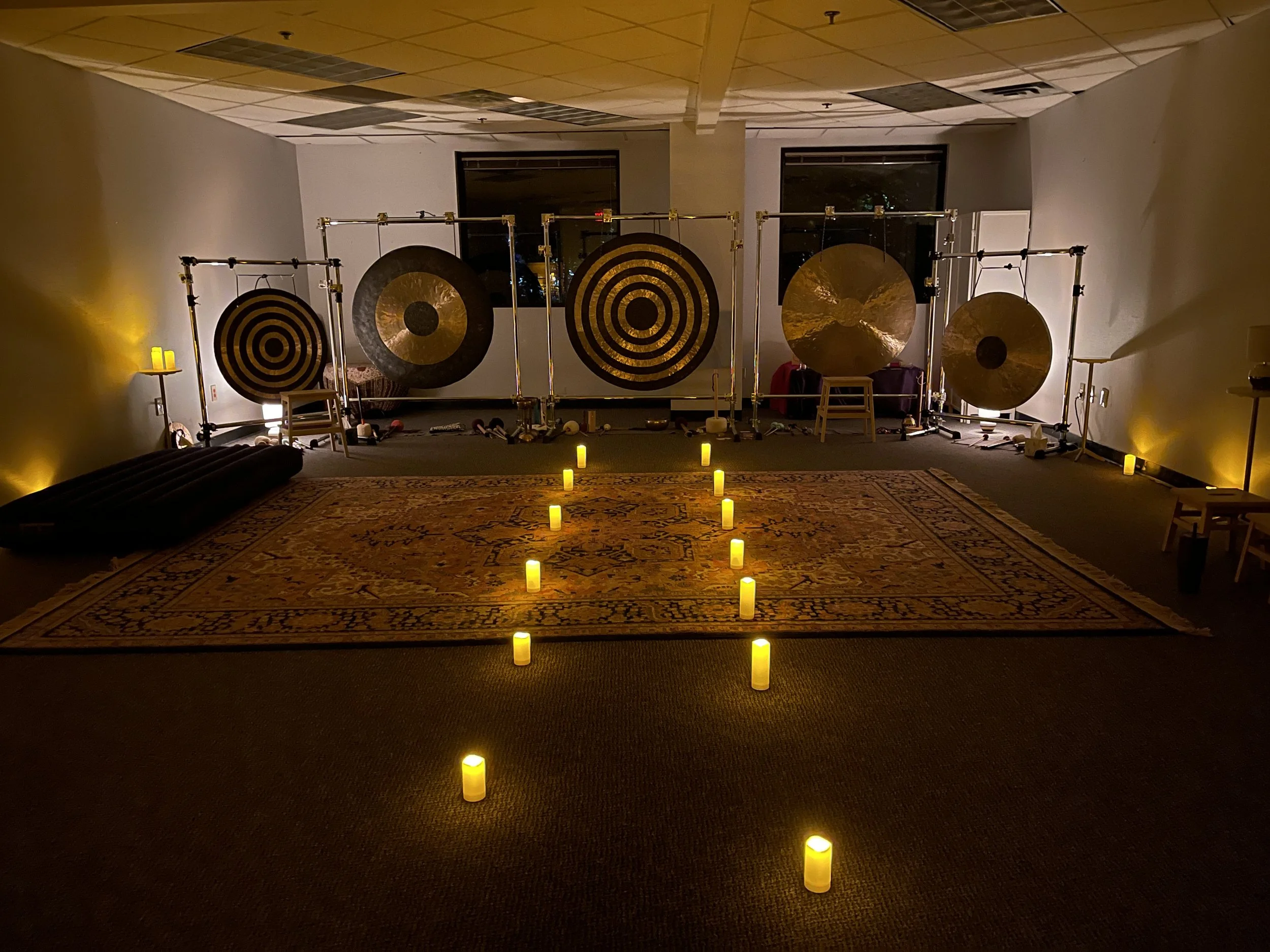 Wall of gongs at the front of the studio and an aisle of candles leading to the biggest gong.