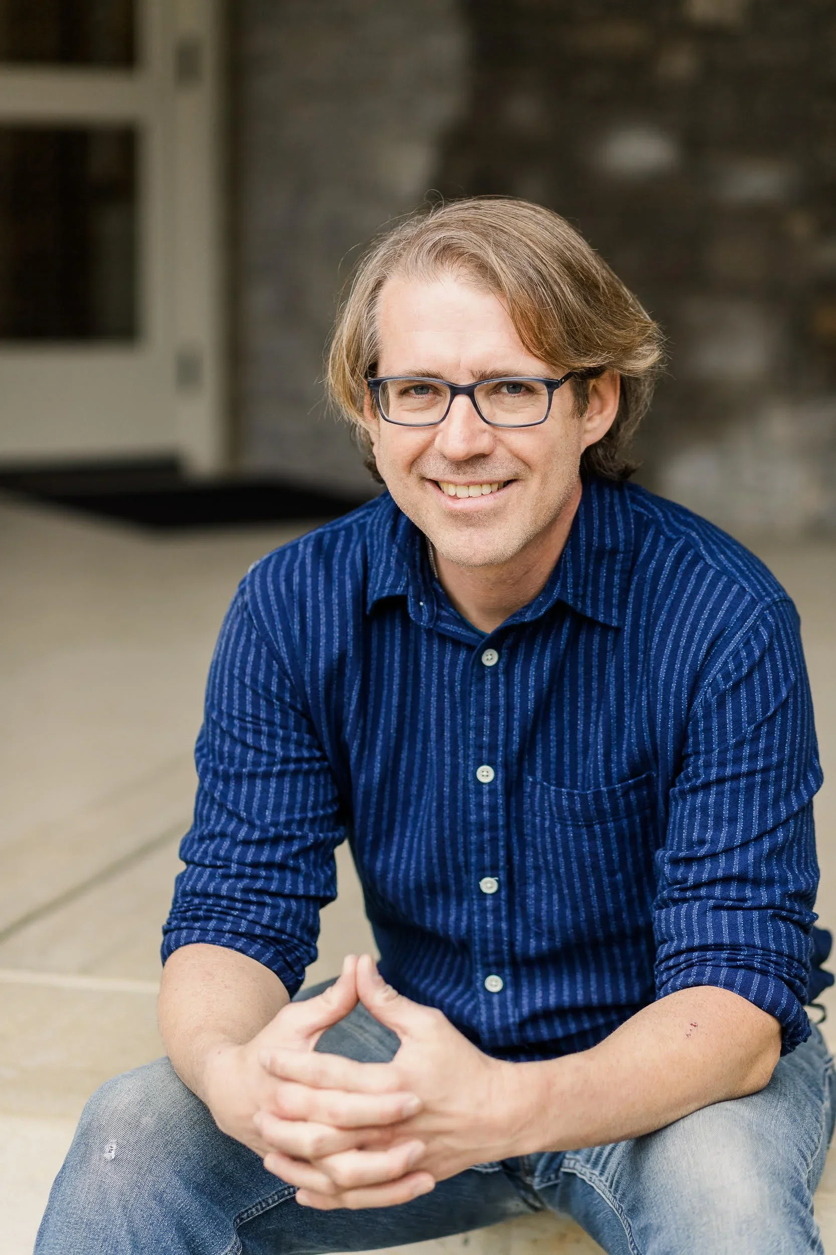 A photo of Eric Bates seated and smiling at the camera.