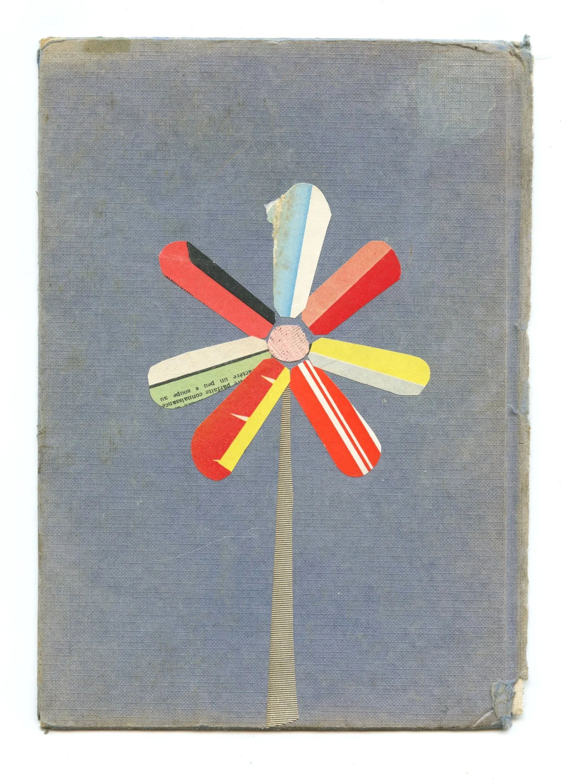 A paper collage depicting a flower with colourful petals. Created on a worn blue vintage book cover.