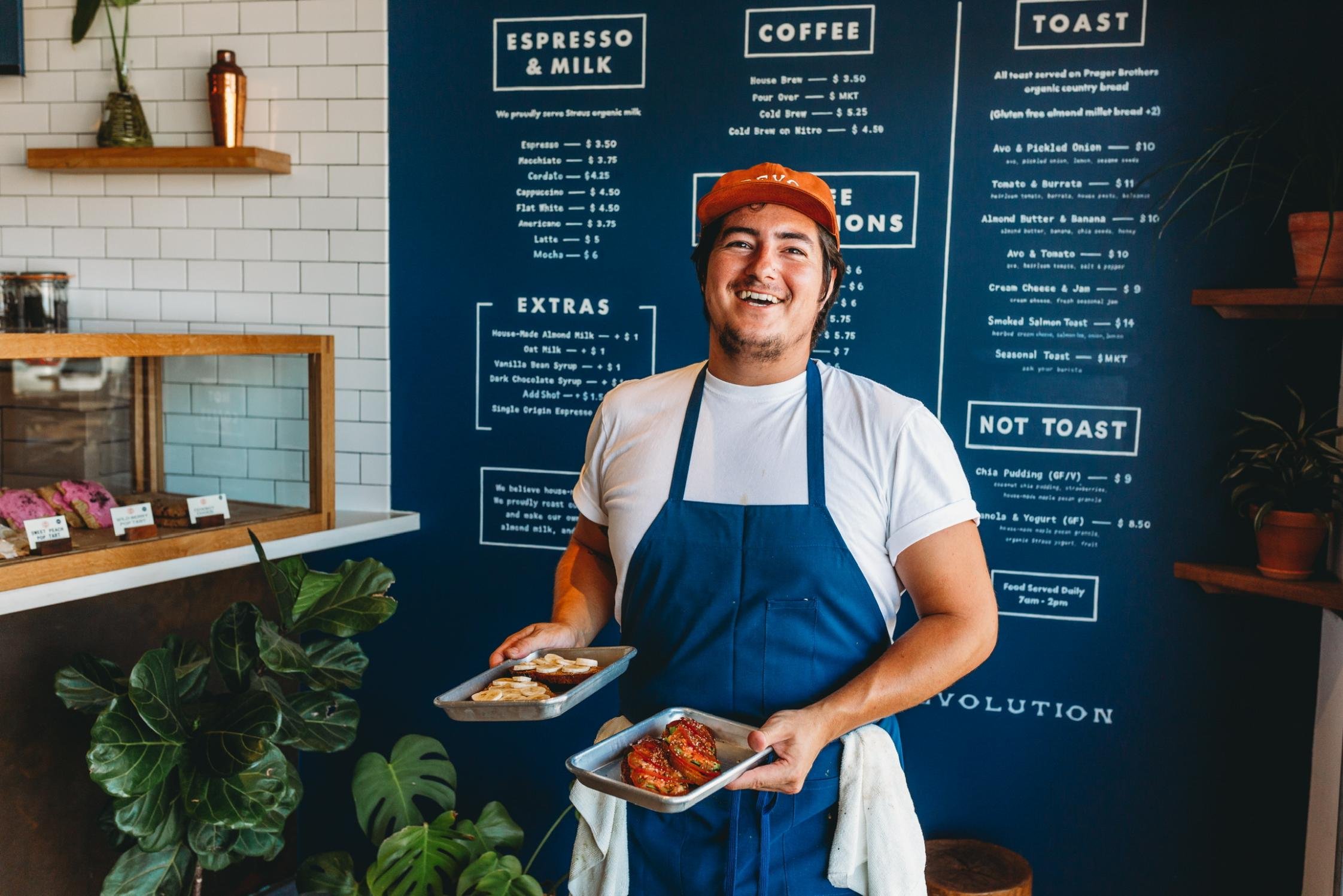 Revolution Roasters Cook Holding Plates of Toast in front of Menu.jpg