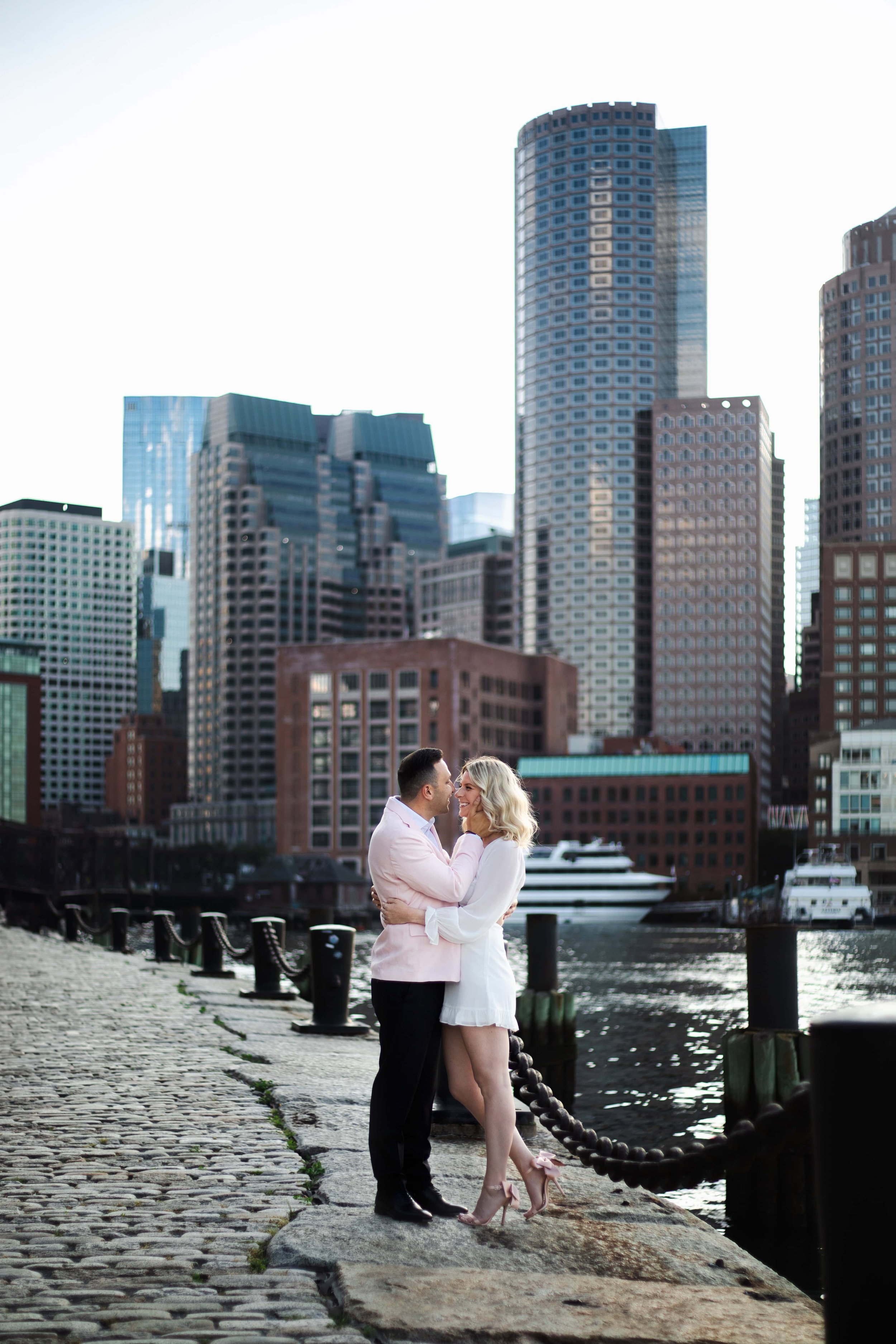 Engagement session at the Boston seaport with the skyline behind the couple