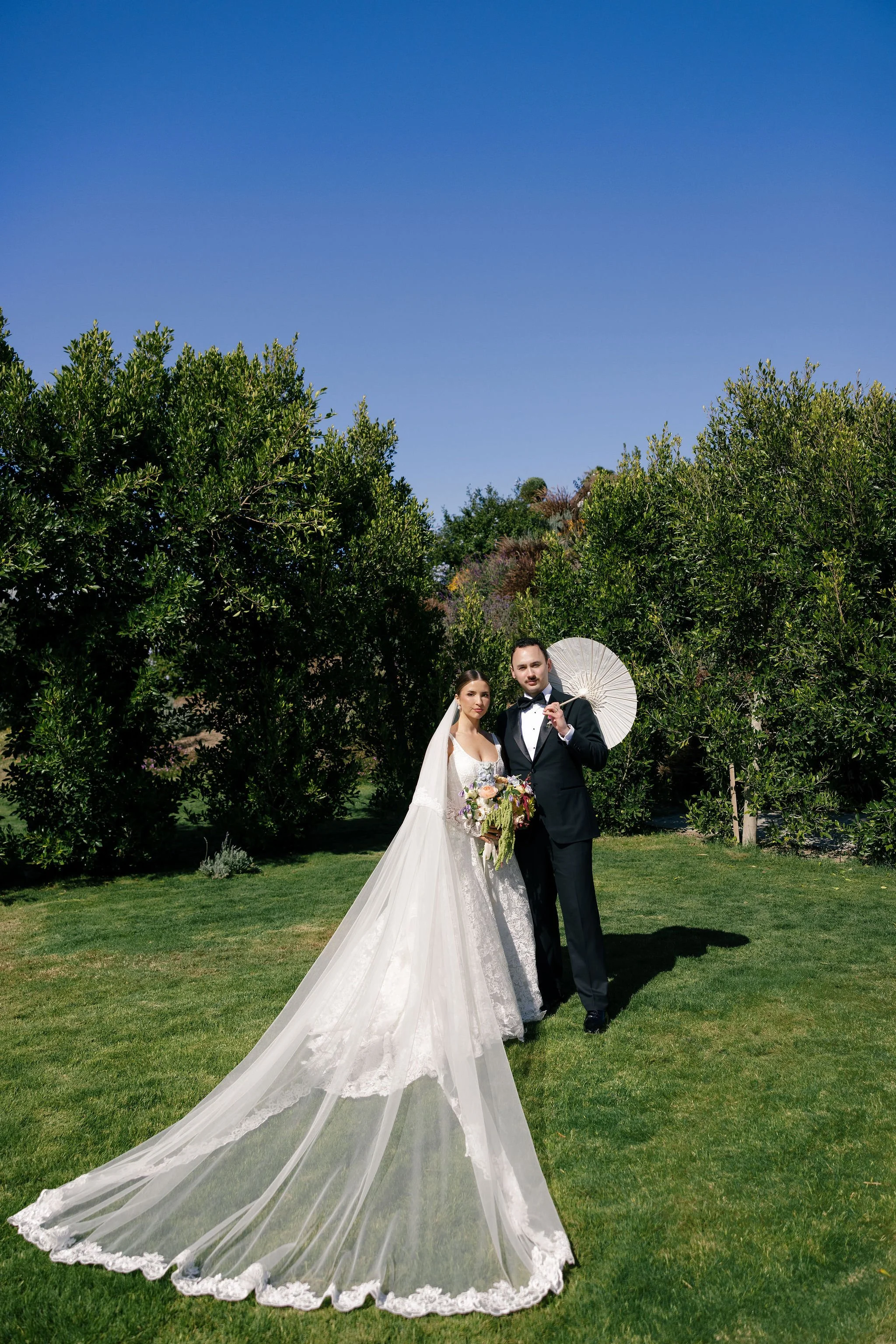 bride and groom posing for editorial photo on lawn bright blue sky, film coloring