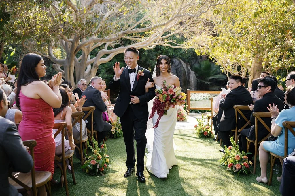 Couple walking back down aisle after getting married, rich red and green toned florals