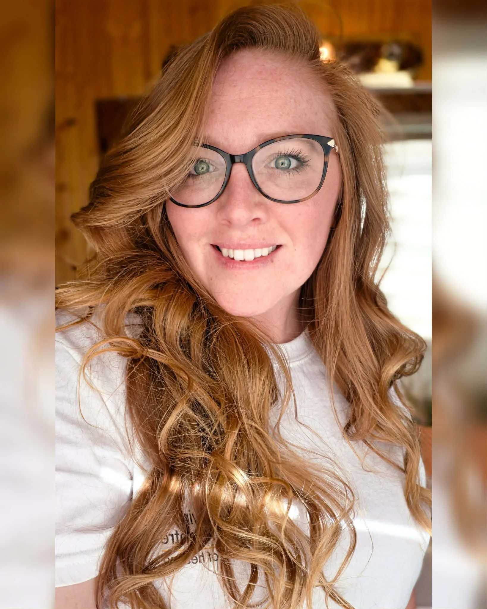 Red haired girl with glasses gently smiling