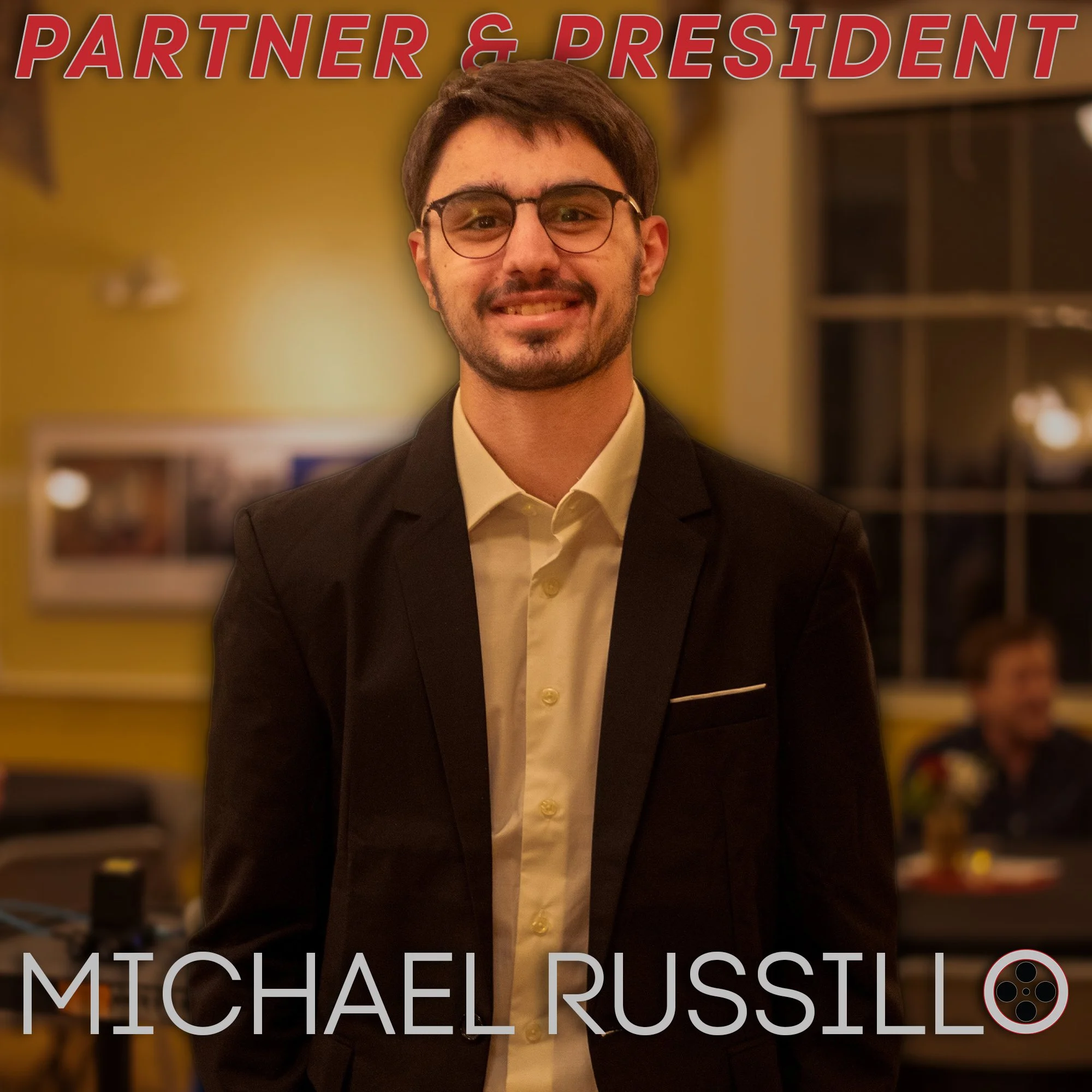 A man in a suit smiling at a party or social gathering at night with yellow walls and a window in the background. Text overlays say 'Partner & President' at the top and 'Michael Russillo' at the bottom.
