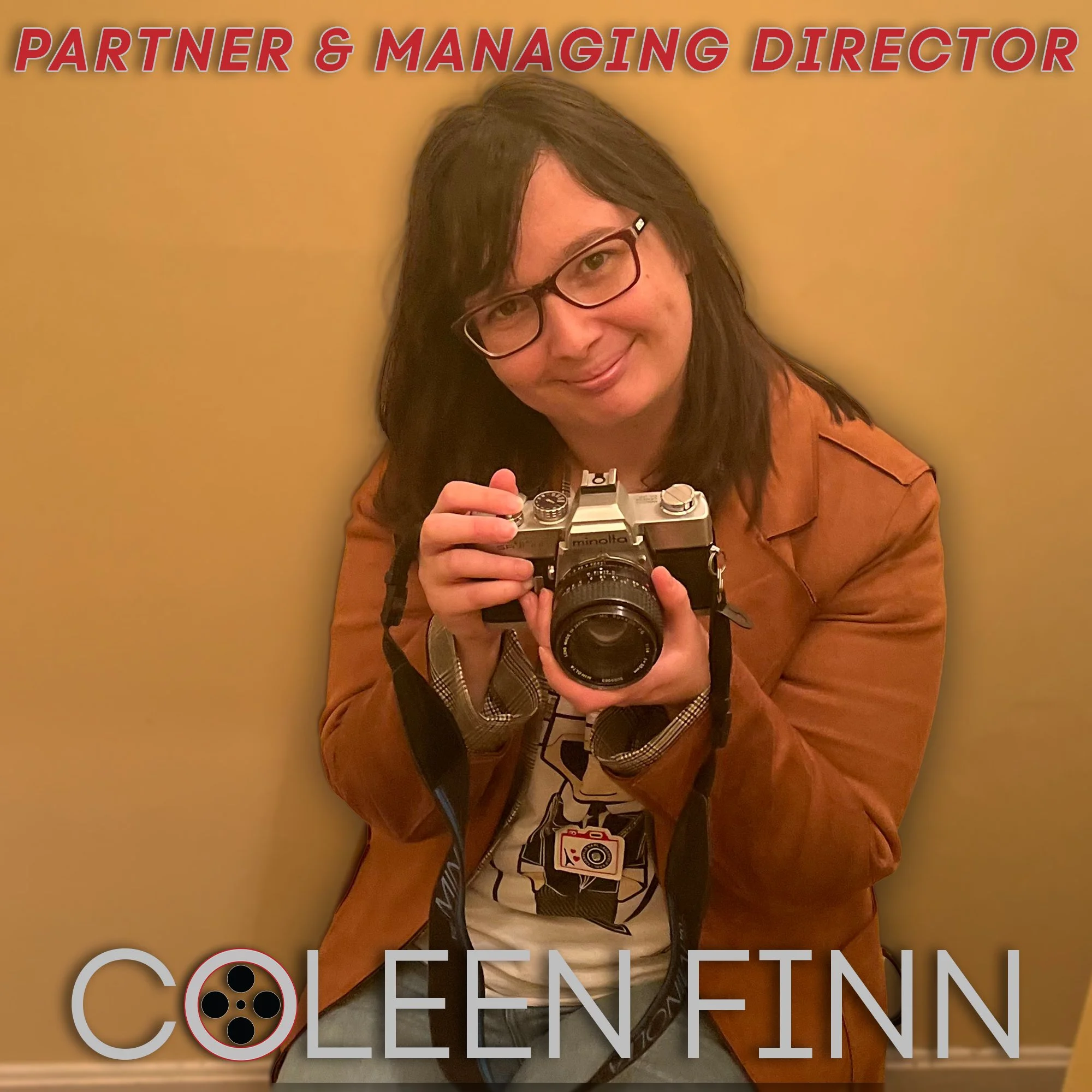 A woman with glasses and dark hair holding a vintage camera, smiling, with a beige background and red text at the top reading "Partner & Managing Director" and gray text at the bottom reading "Colleen Finn".