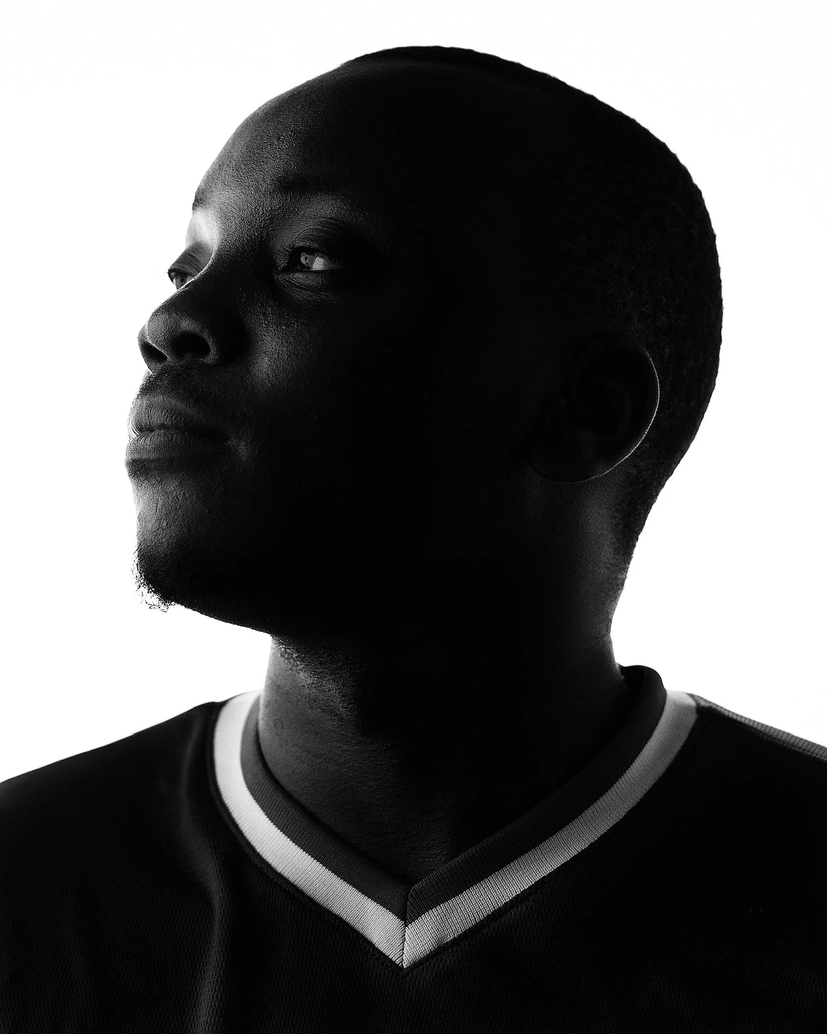 Black and white side portrait of a young man with short hair, wearing a sports jersey, looking to the left.