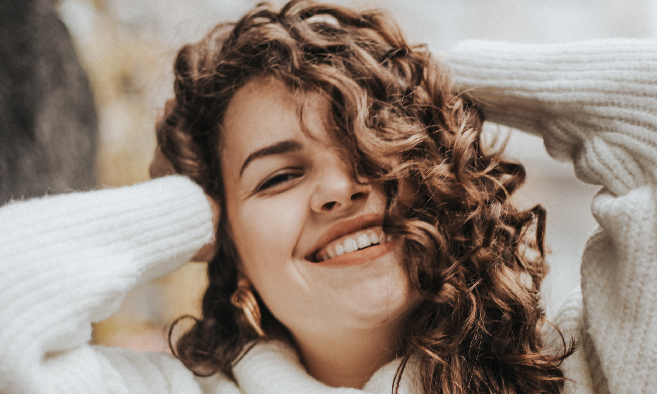 A woman holding her hands on her head smiling as she gently gives herself compassion over criticism allowing her to make a career change.