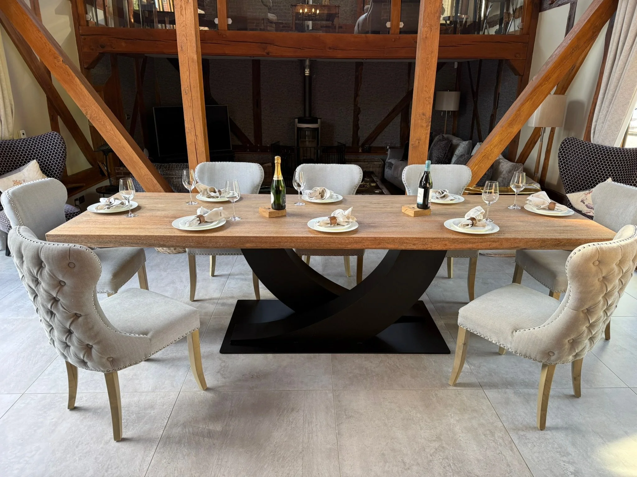 A dining table set for a celebration, with eight white upholstered chairs around it, and a bottle of champagne and wine on the table.