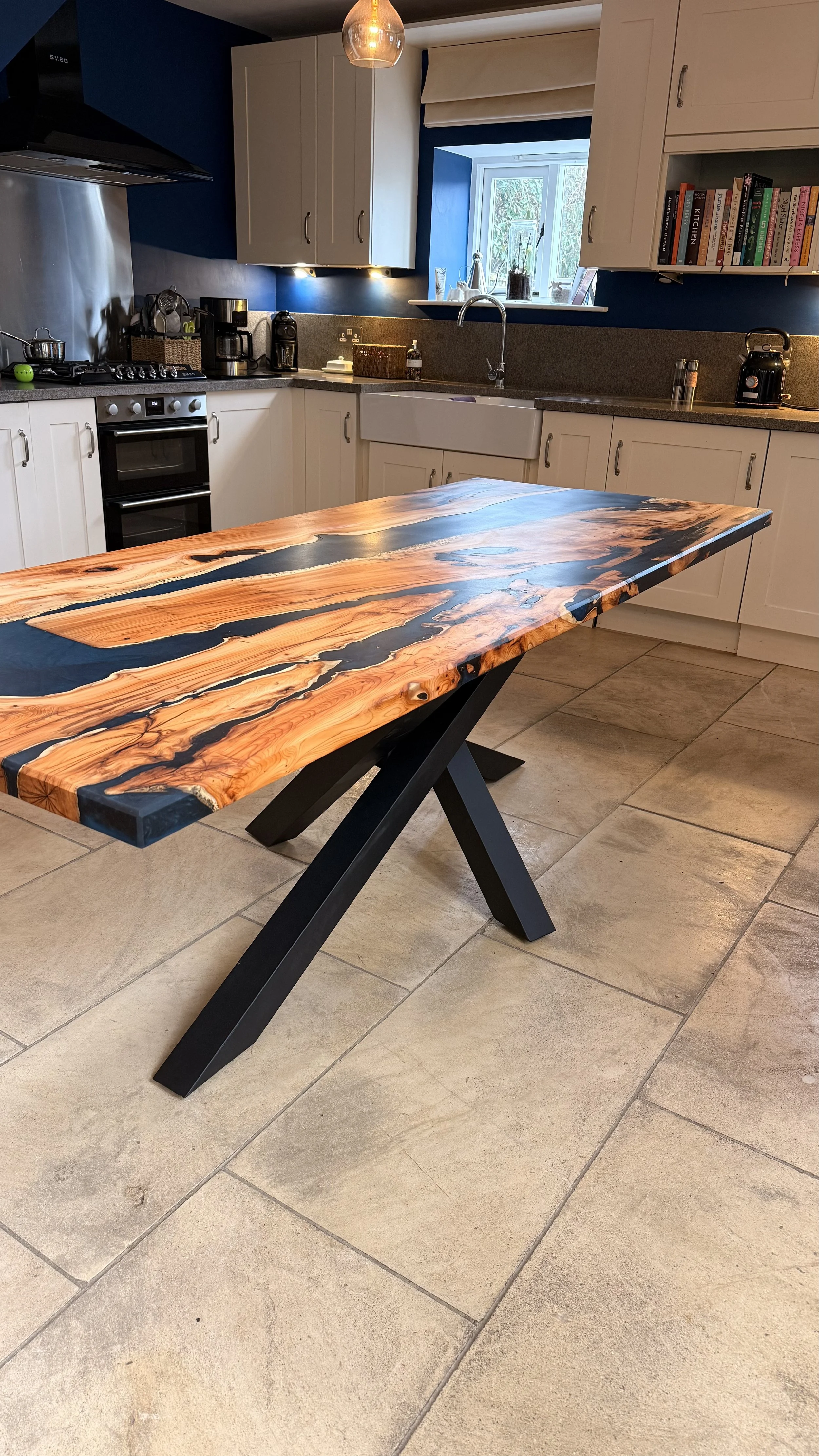 A kitchen with white cabinets, a blue wall, and a wooden table with black accents.
