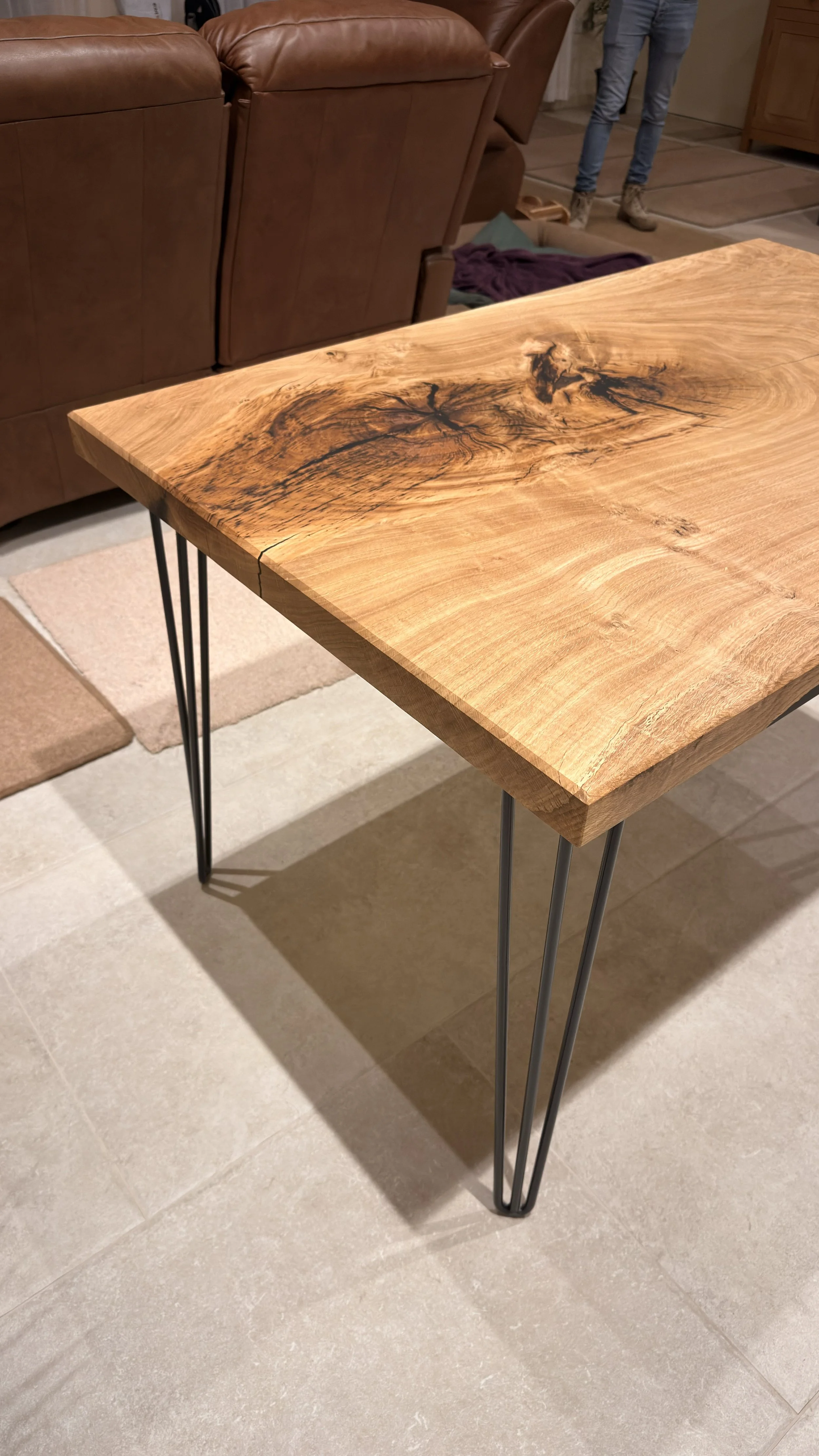 A wooden table with black metal hairpin legs in a living room setting.