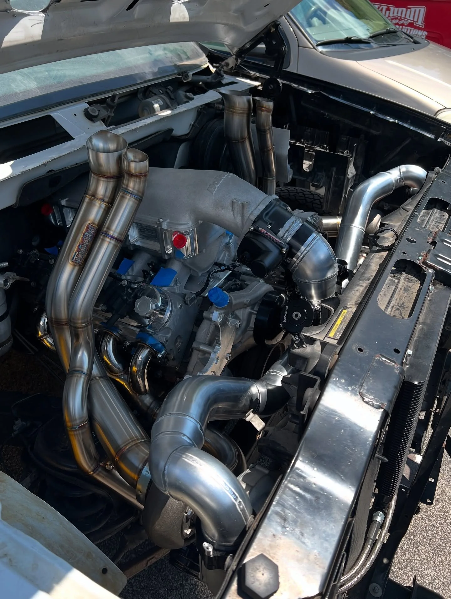 Car engine with exposed pipes and components, likely a race or performance vehicle.