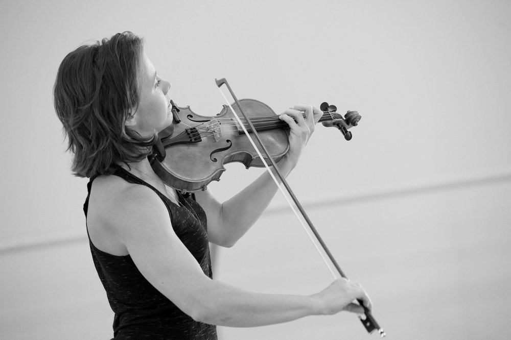  Sarah playing her violin, angled slightly upward. The camera is positioned on her right side, so her hands are very visible on the strings and bow. 