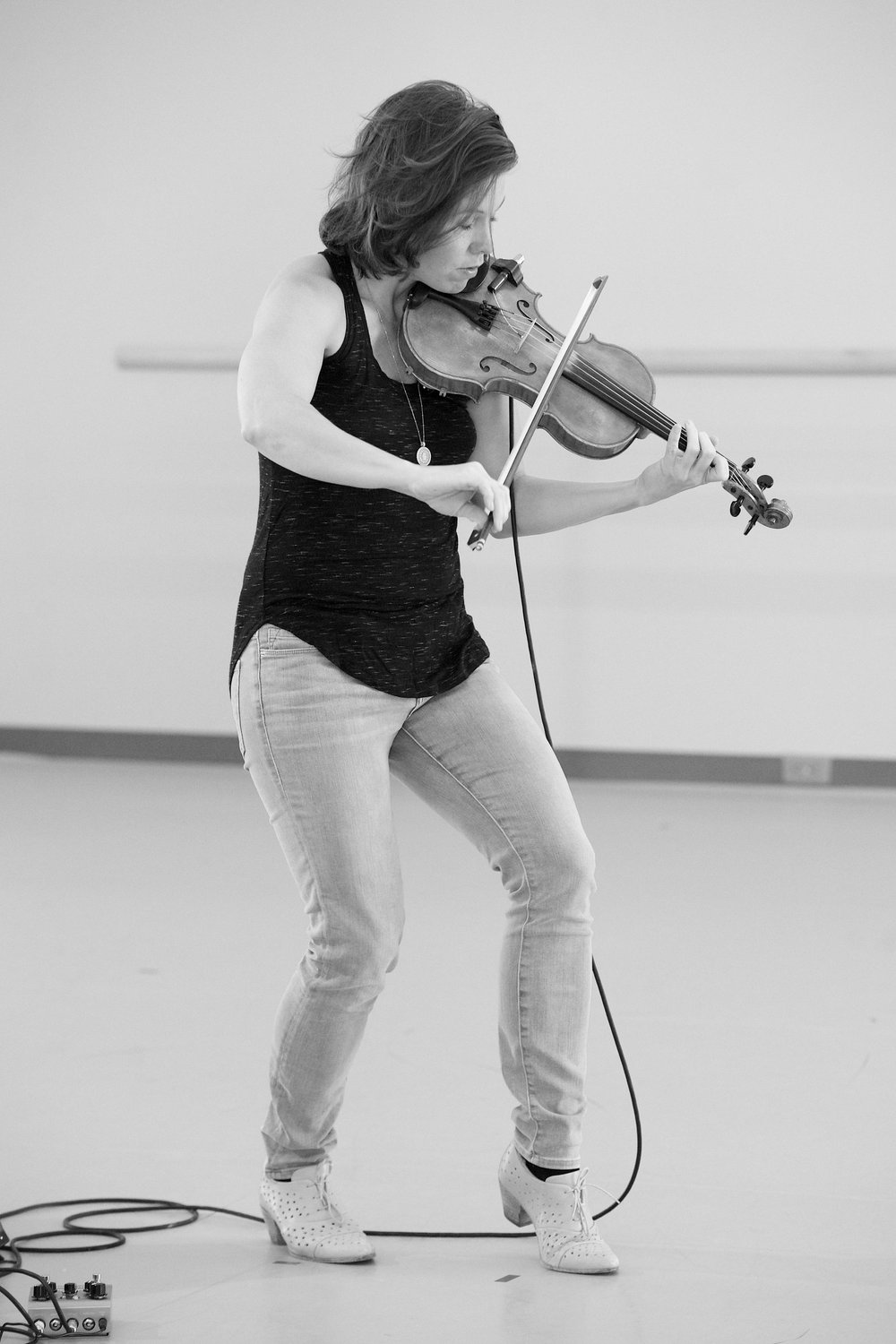  Sarah playing her violin in rehearsal. Her knees are bent, and she is leaning slightly forward.  