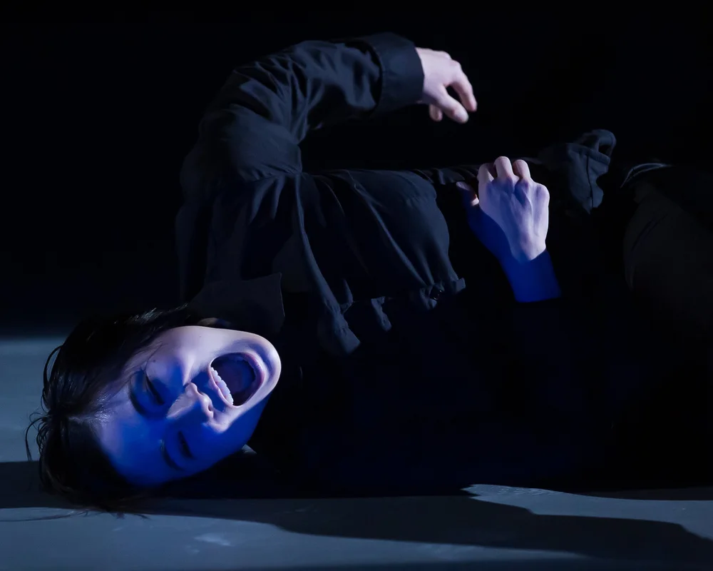  Sahara Morimoto lying on her side on the stage, facing the camera. She is screaming.&nbsp; 