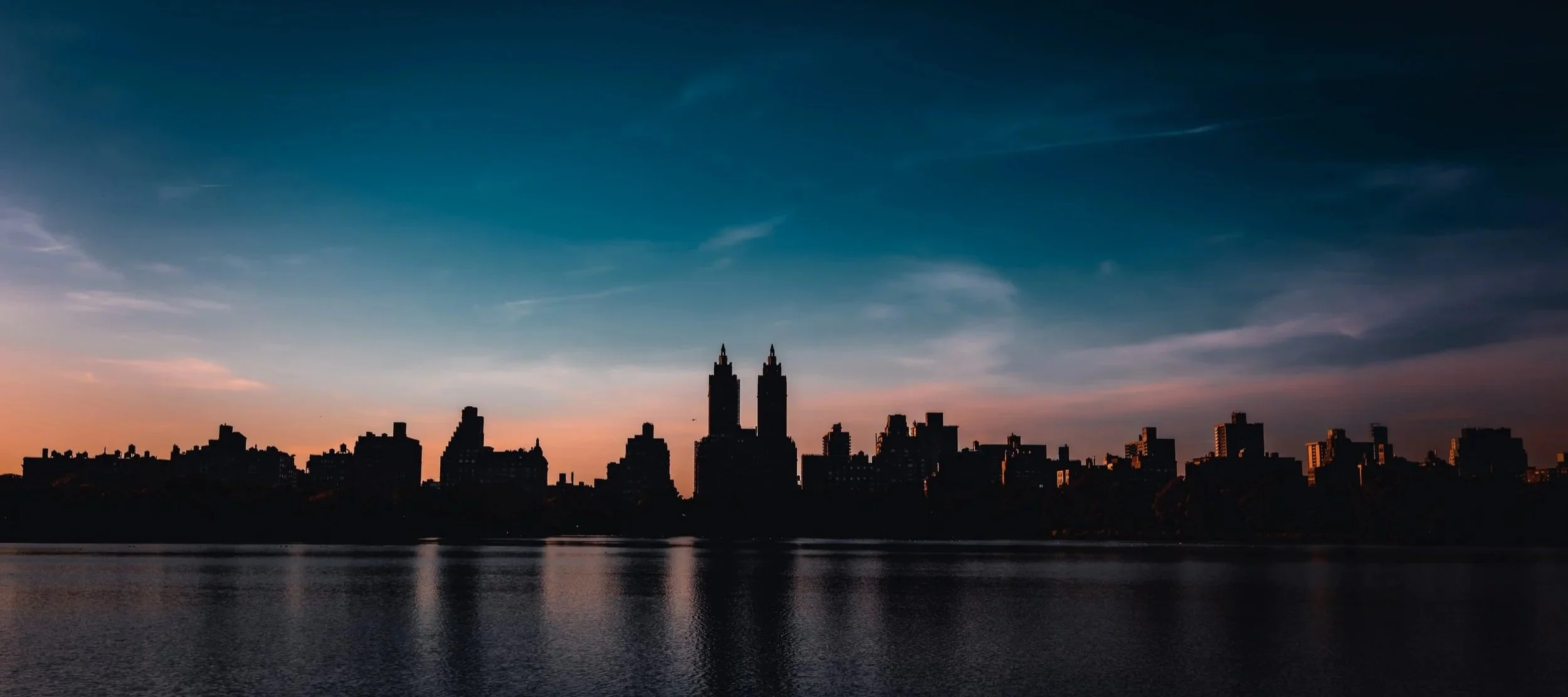 Fine Art cityscape photo of a part of the New York City skyline shot accross the water reservoir in Central Park with the sun setting behind the buildings of the Upper West Side of Manhattan