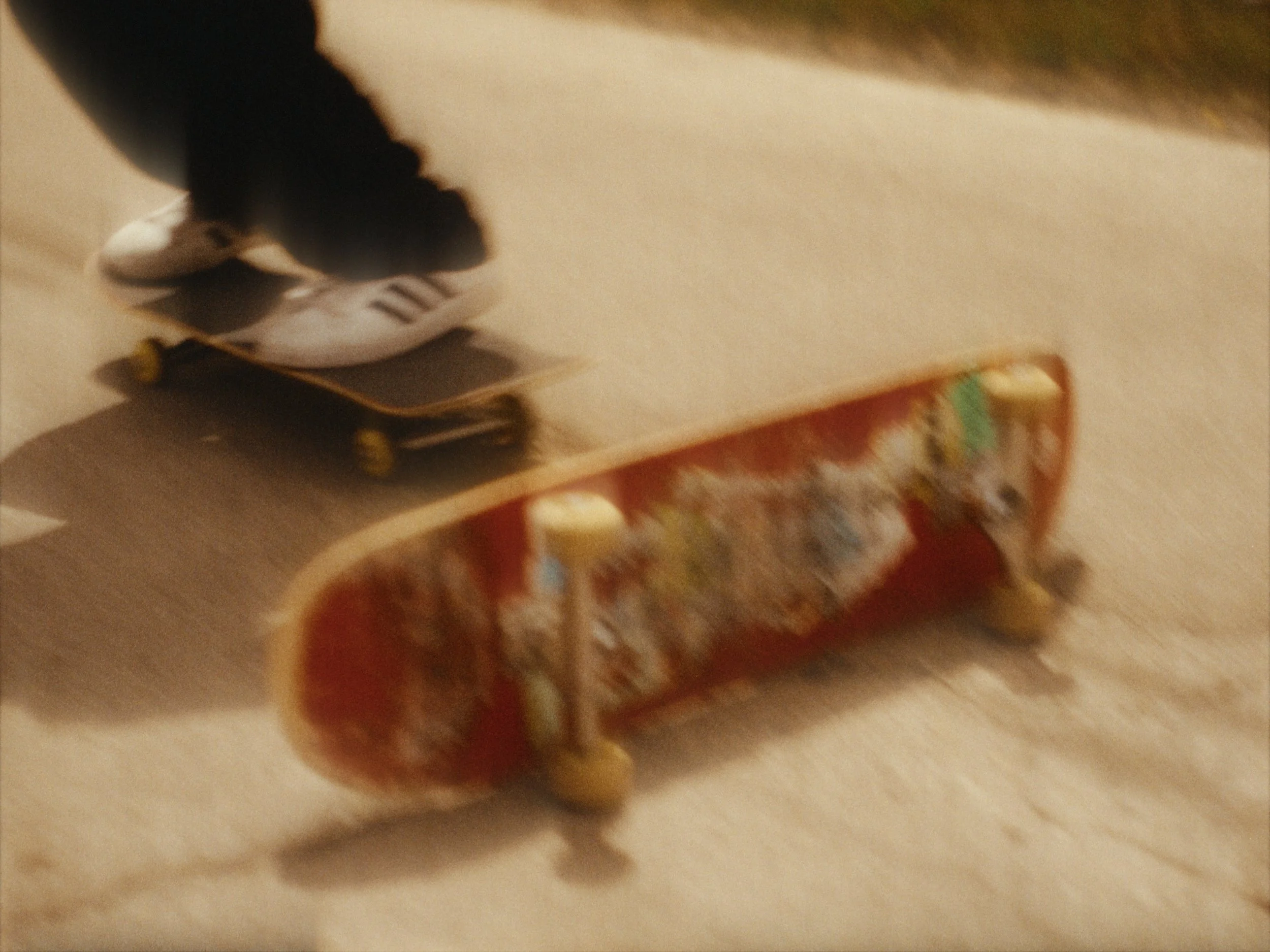 A skateboard resting against a wooden piece of furniture in a room with a beige carpet. The skateboard has a dark deck with yellow wheels.