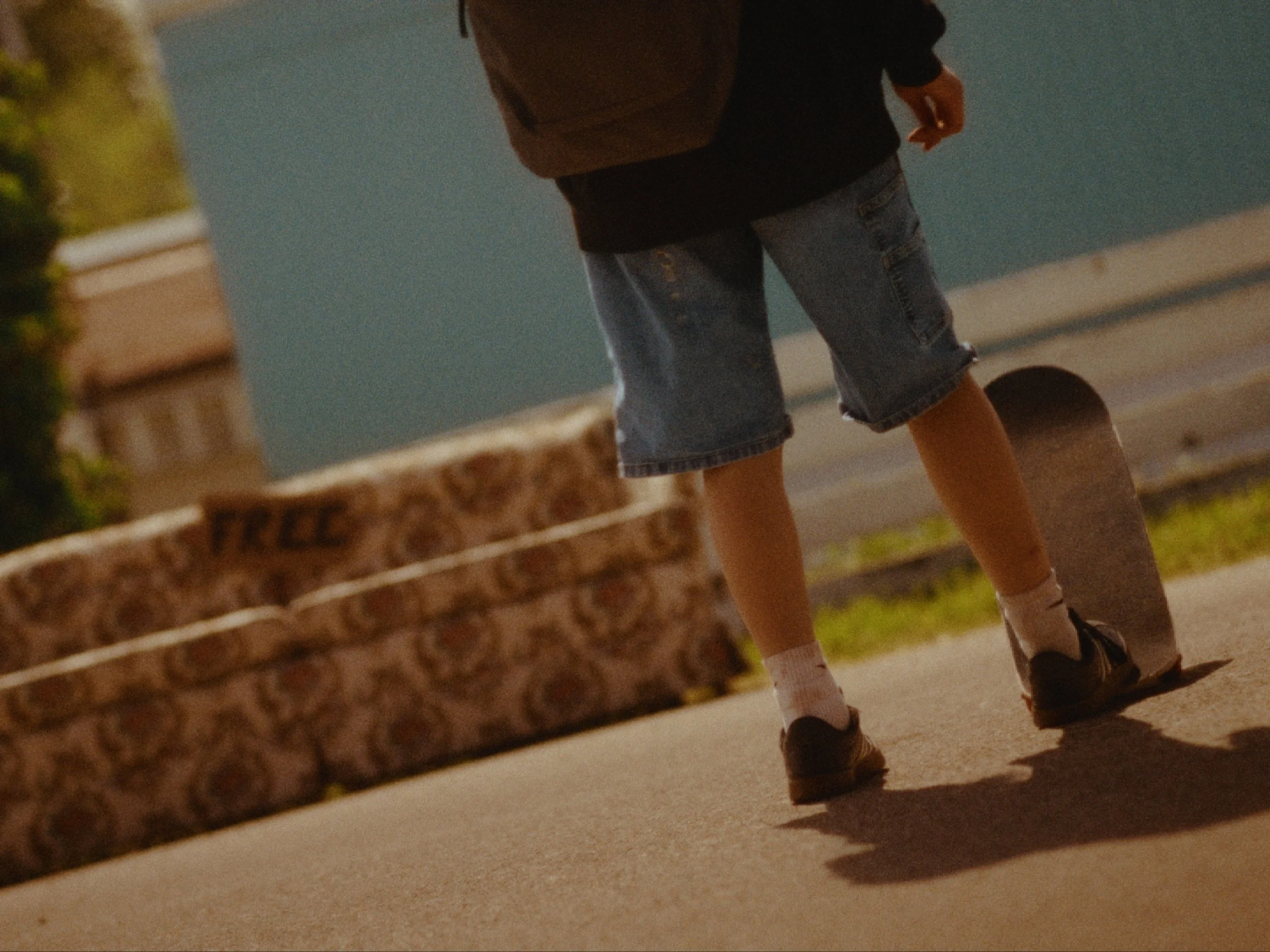 A child wearing shorts, black shirt, and sneakers standing next to a brick wall.