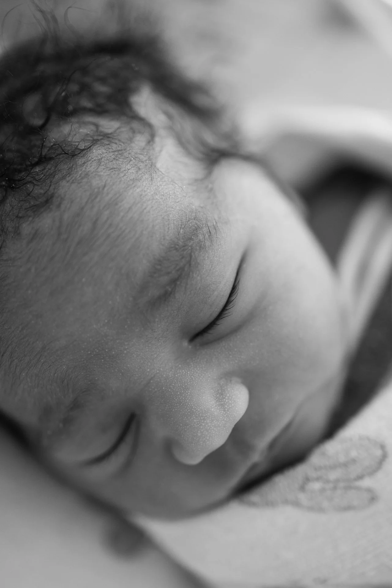 Close-up black and white photo of a person's face with eyes closed, focusing on the eyelashes, eyelid, and nasal bridge.