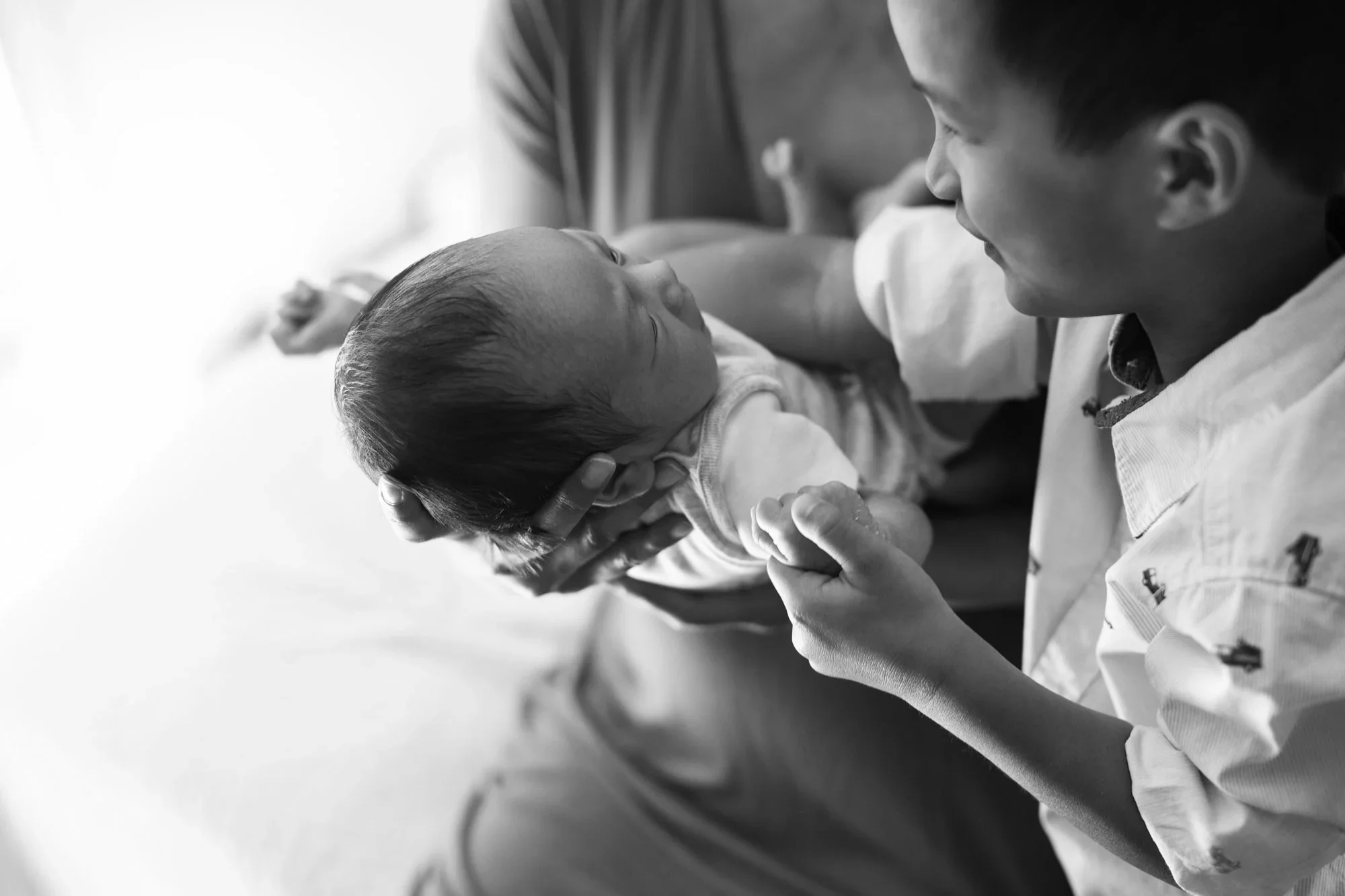 A doctor holding a newborn baby and looking at it with affection in a hospital setting.