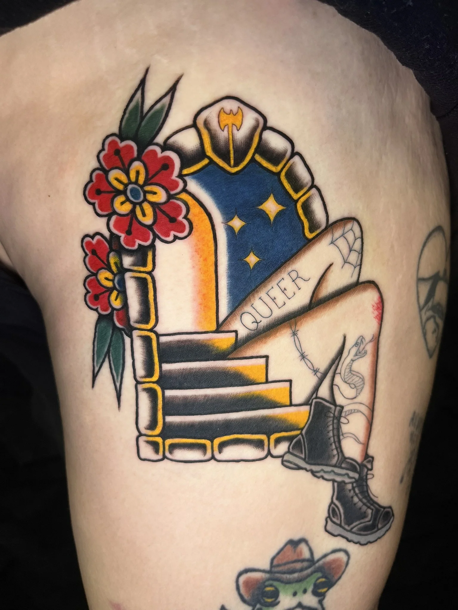 A stone portal crowned in an axe with two tattooed legs coming out, labeling themselves "Queer"