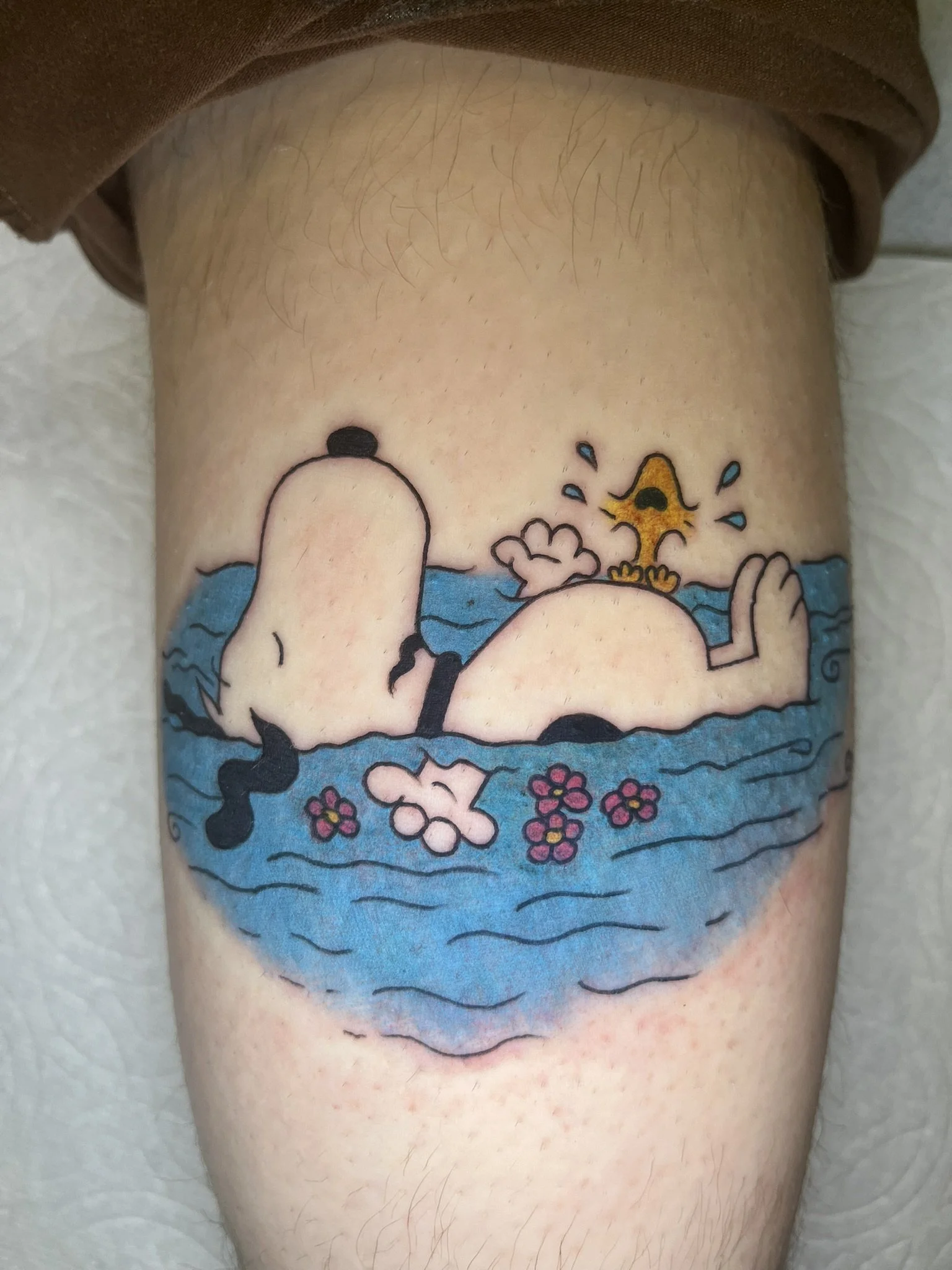 Snoopy, relaxing in the water with Woodstock crying on his belly