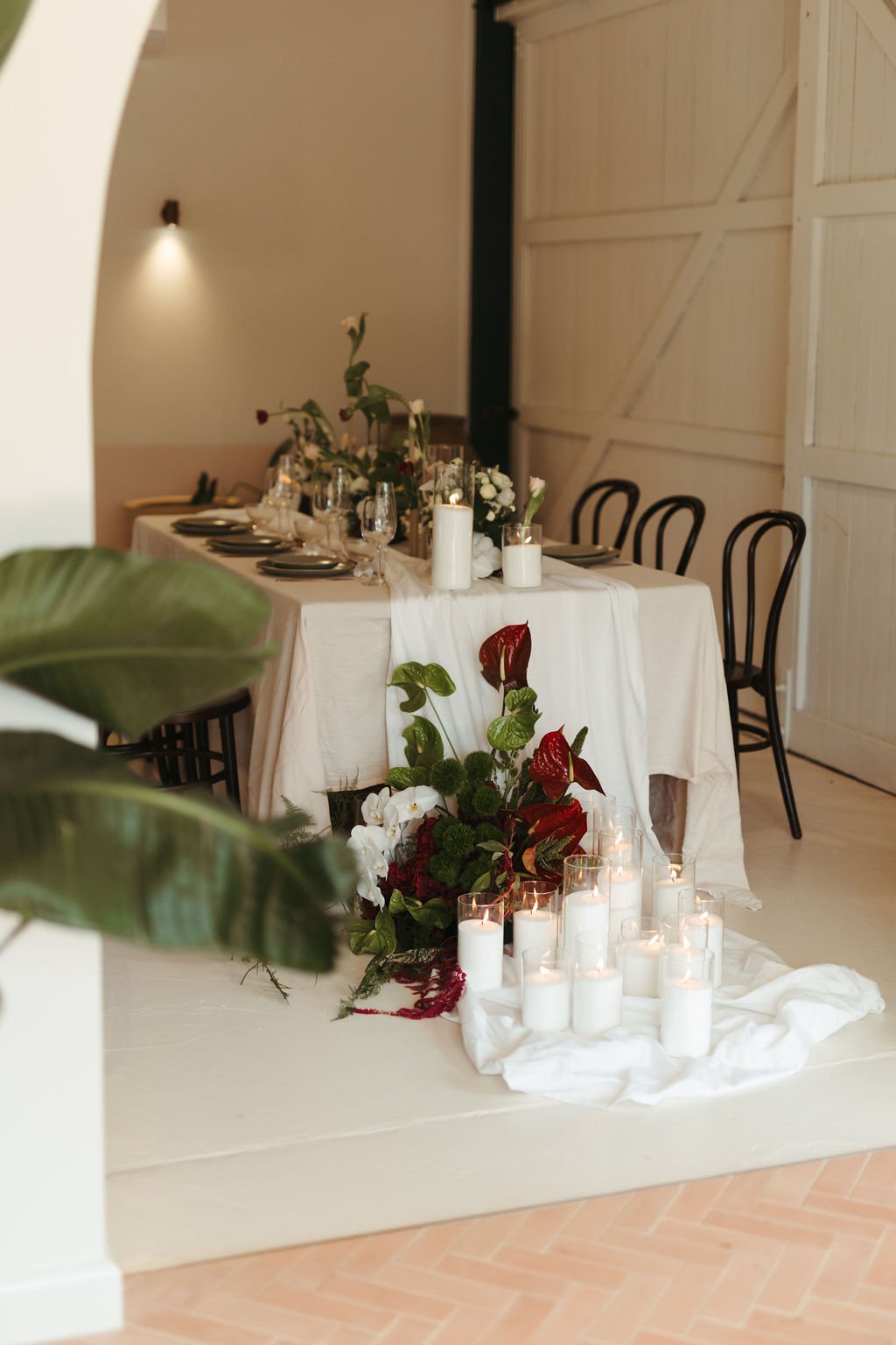 A decorated dining table with candles, flowers, and elegant tableware, set for a special occasion or event in a rustic-style room.