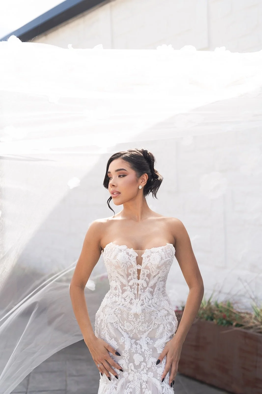A woman wearing a white off-shoulder dress with puffed sleeves and a matching choker, posing against a plain white background.