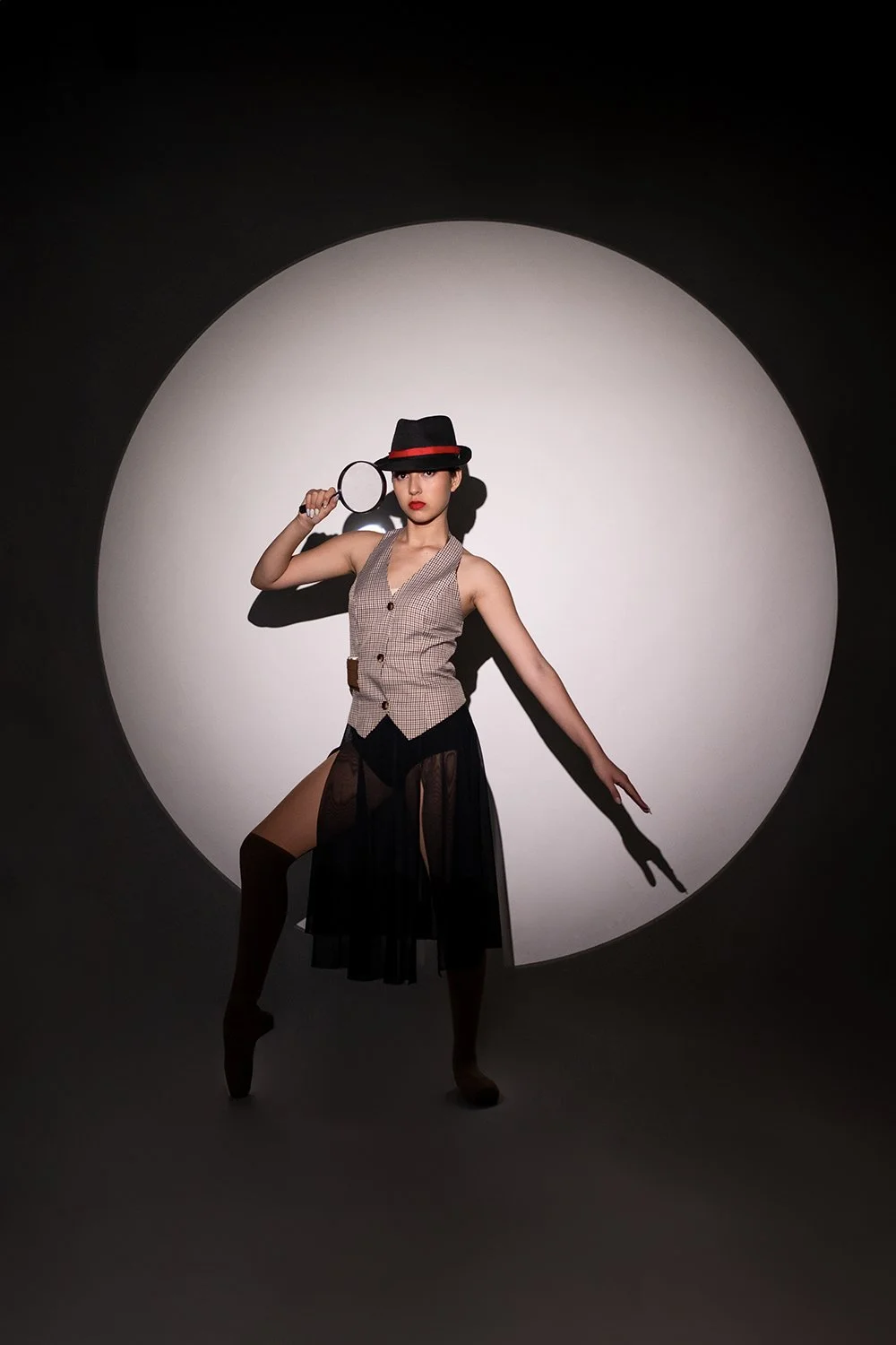 Dancer holding magnifying glass in spotlight