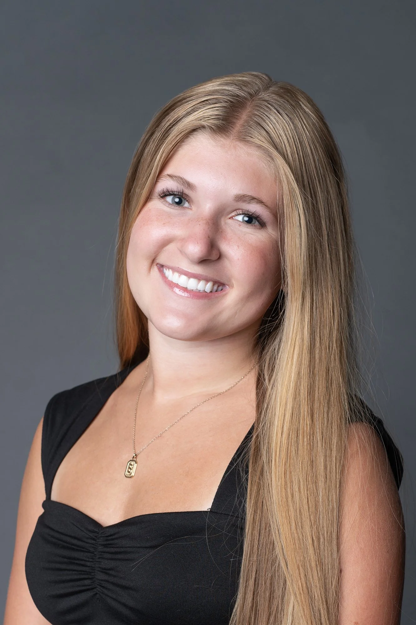 Headshot of student dance teach in black top and gold necklace