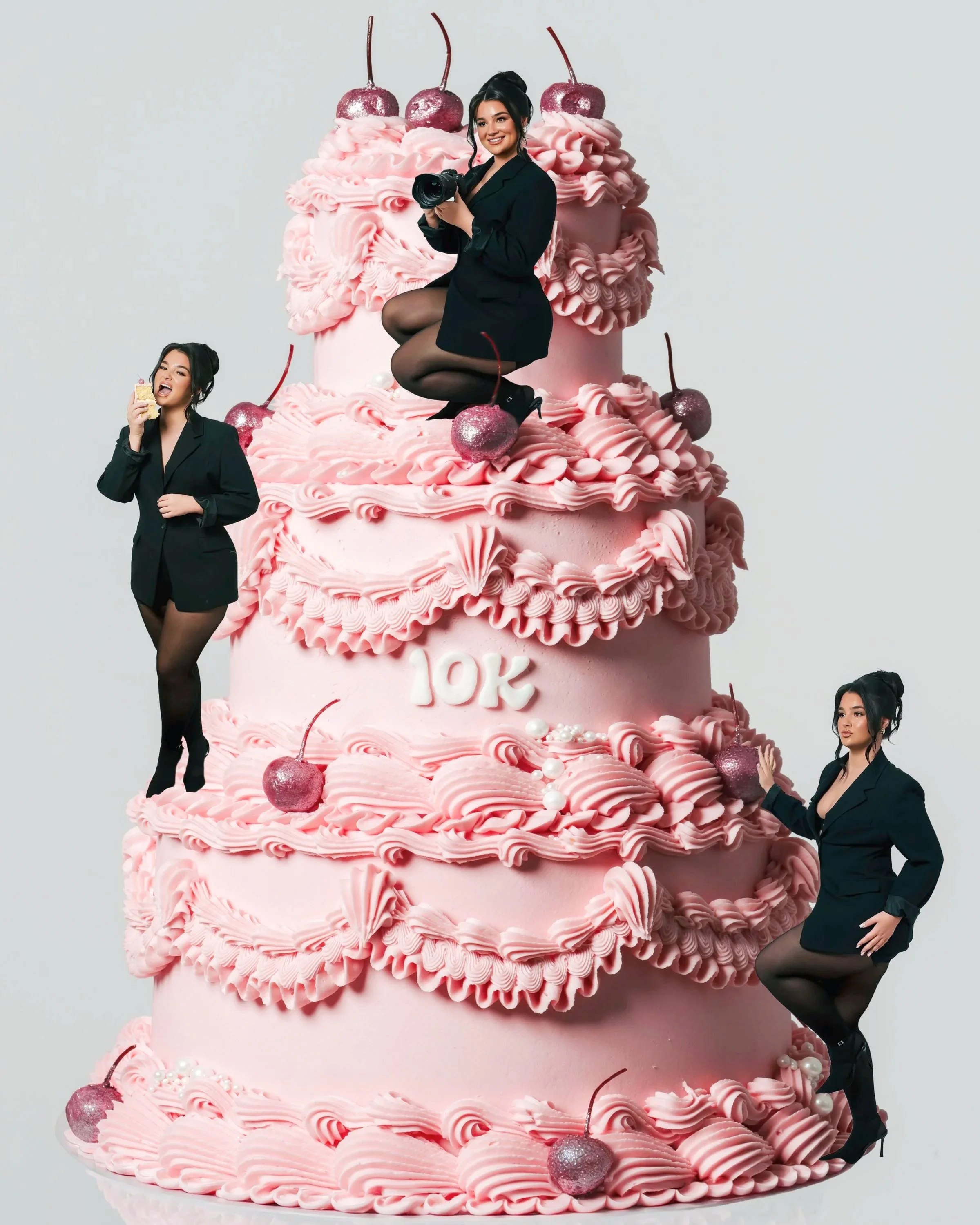 Large pink layered cake decorated with cherries and ruffles, with four women in black outfits posing around it. The cake has '10K' written on it, celebrating 10,000 followers or subscribers.