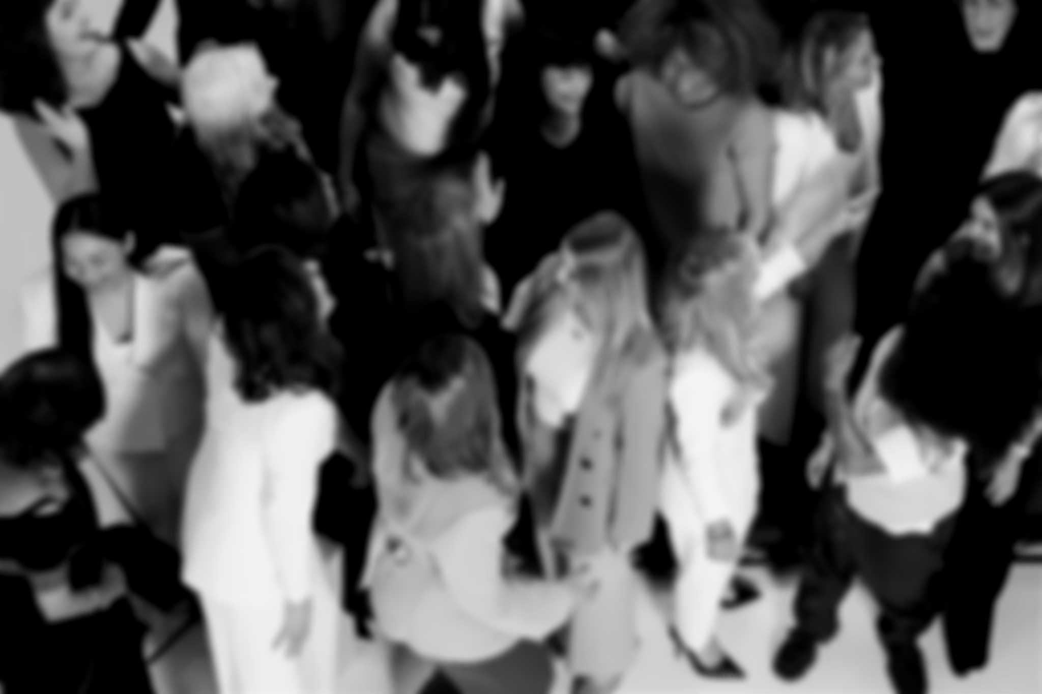 A group of people dressed in formal and casual clothing gathered closely together, seen from above.