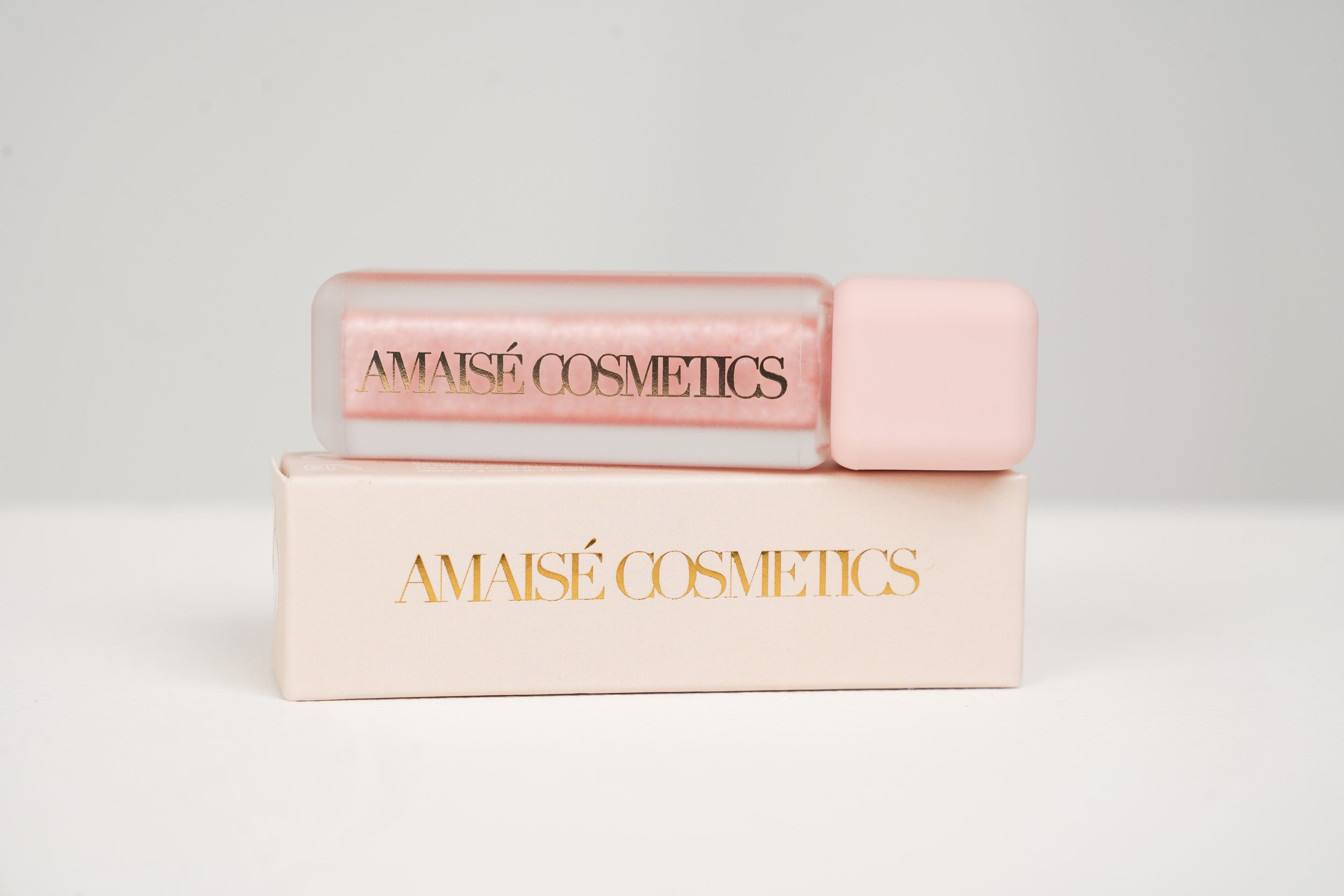 Pink and clear cosmetic product packaging with gold and black text reading 'AmaiSé Cosmetics.'
