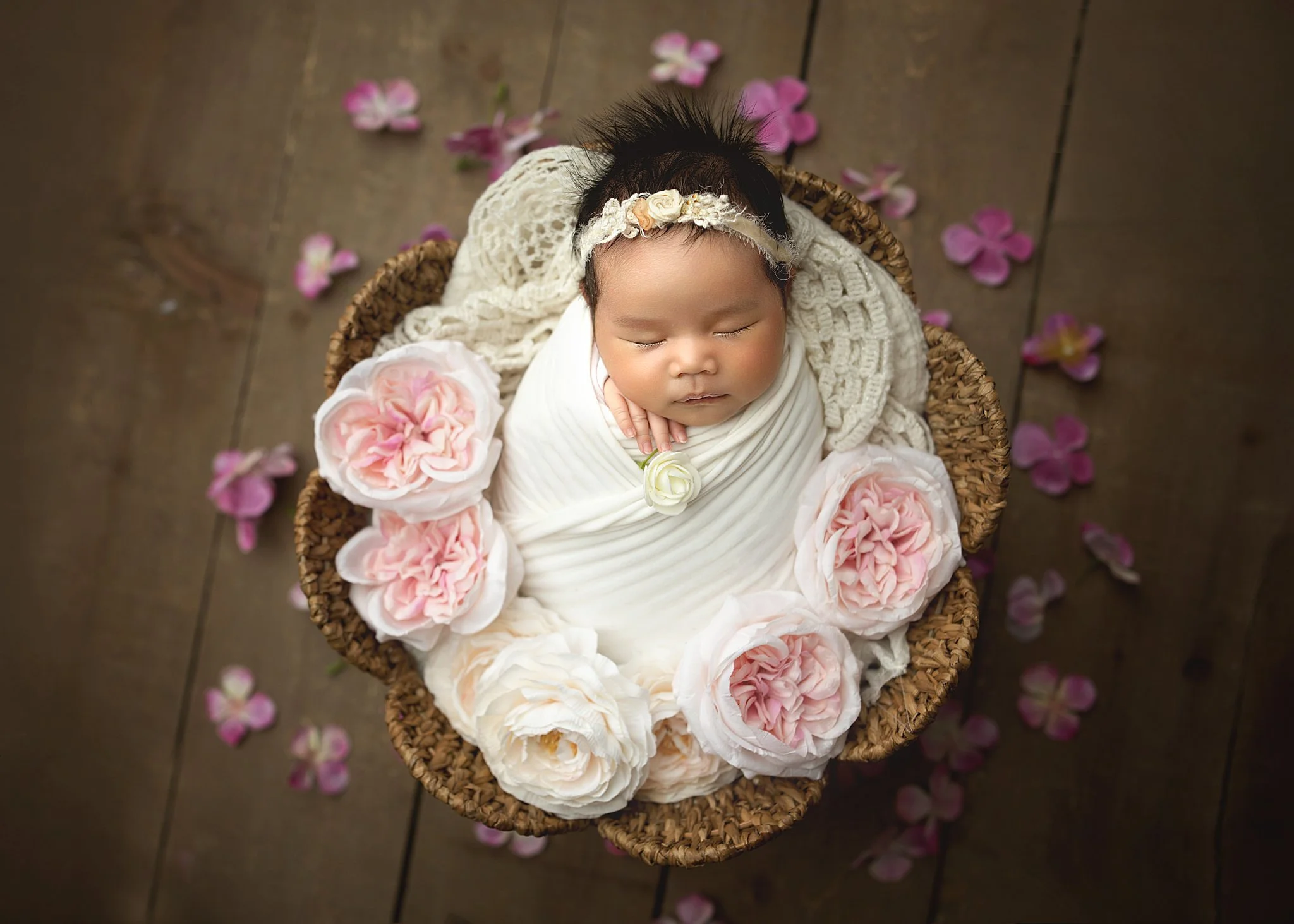 10-day-old newborn baby girl swaddled in a flower basket surrounded by flowers during a professional newborn photo shoot with a Saskatoon newborn photographer.