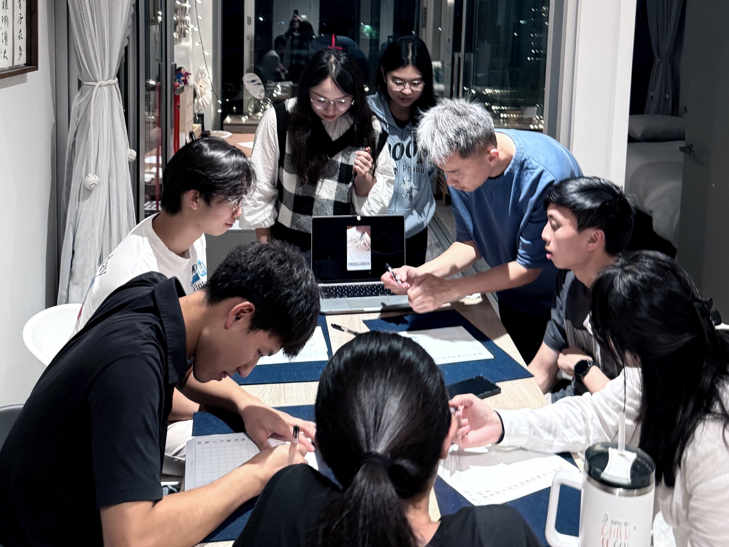 A teacher showing a group of students how to write Chinese calligraphy