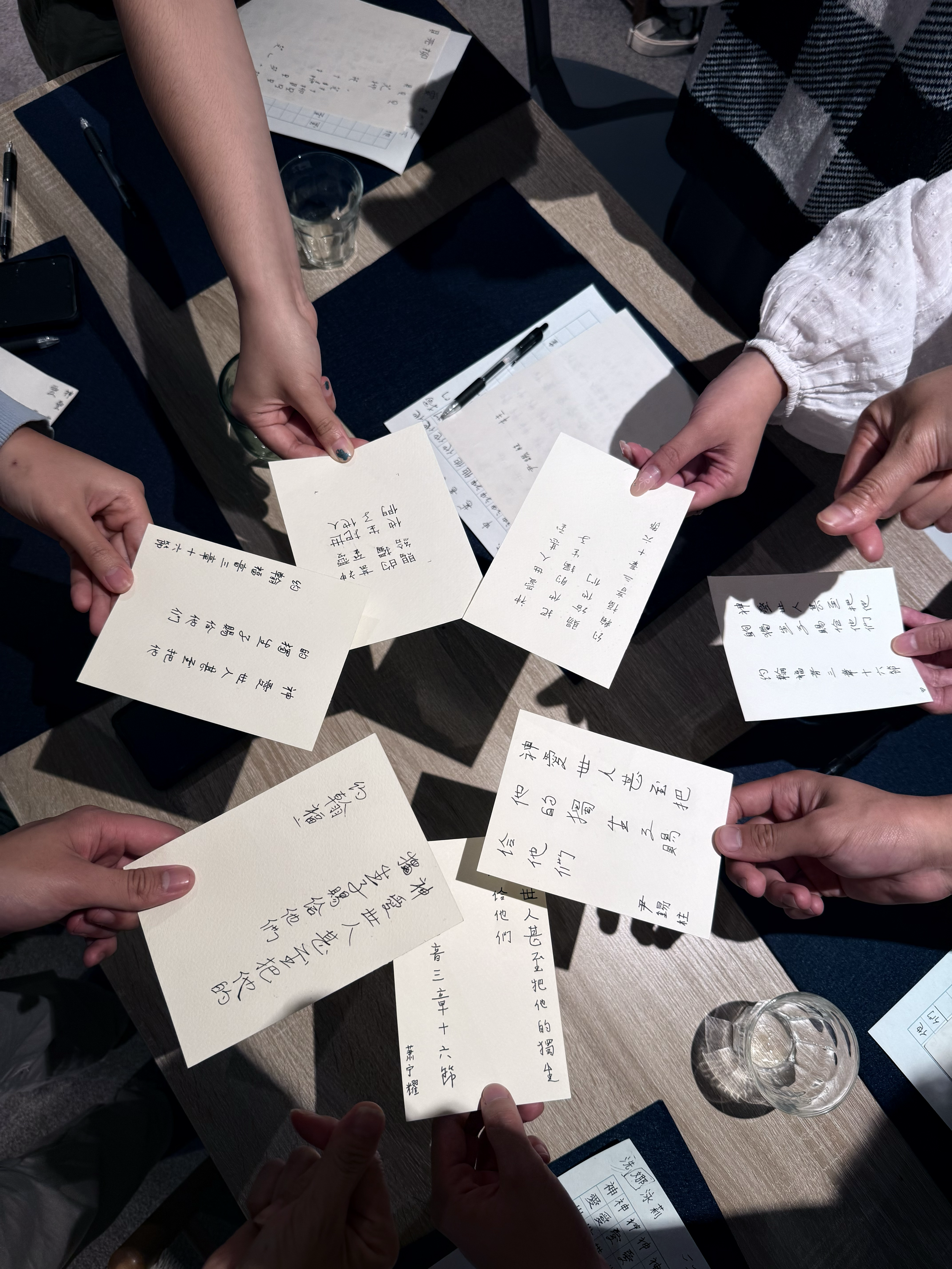 Student showing their Chinese calligraphy written on cards in a circle formation