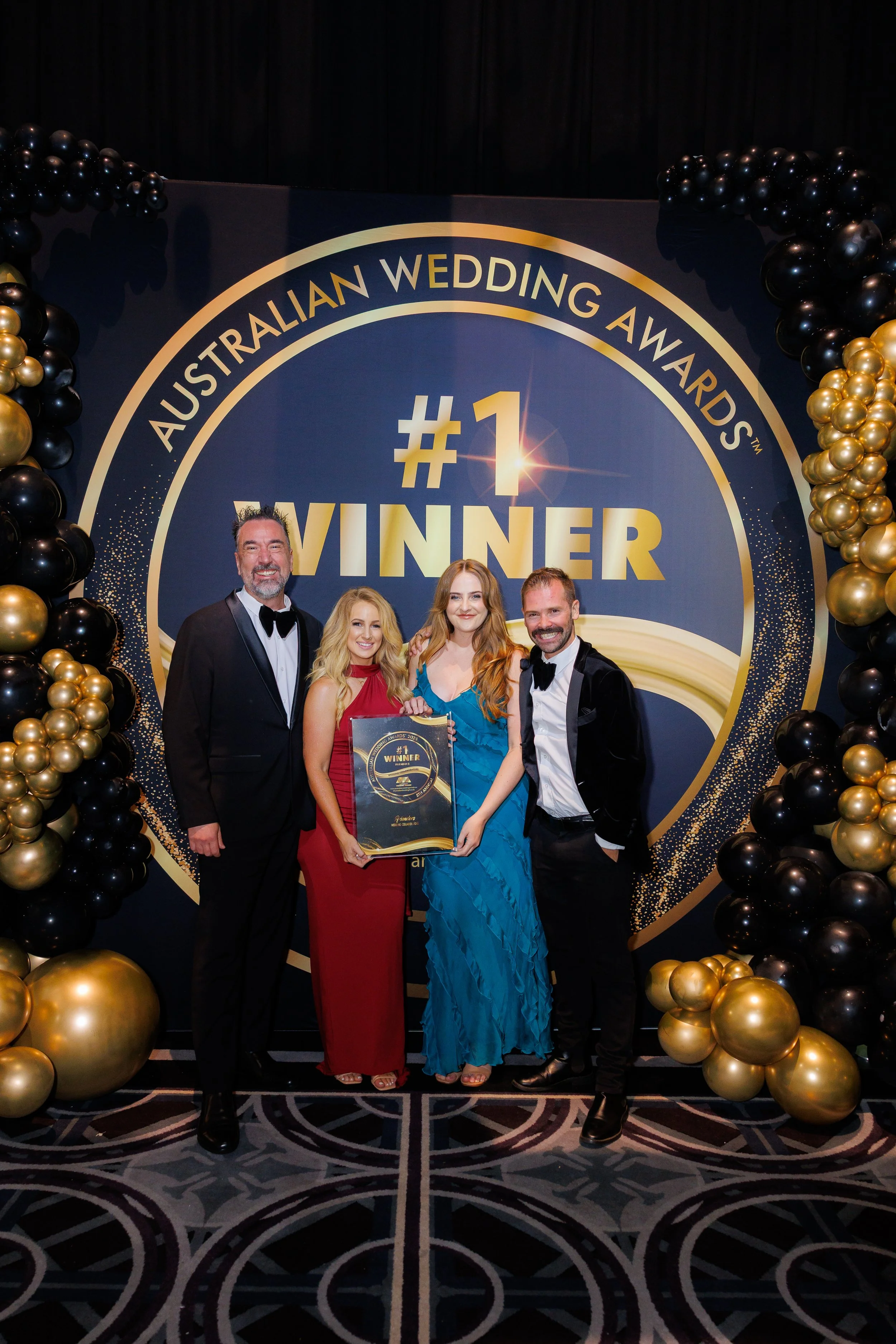 The Friendors are standing infront of a sign that says #1 Winner at the Australian Wedding Awards