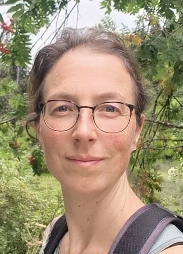 Een portretfoto van een vrouw met schouderlengd bruin haar, die lacht.