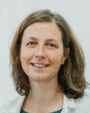 Een portretfoto van een vrouw met schouderlengd bruin haar, die lacht.