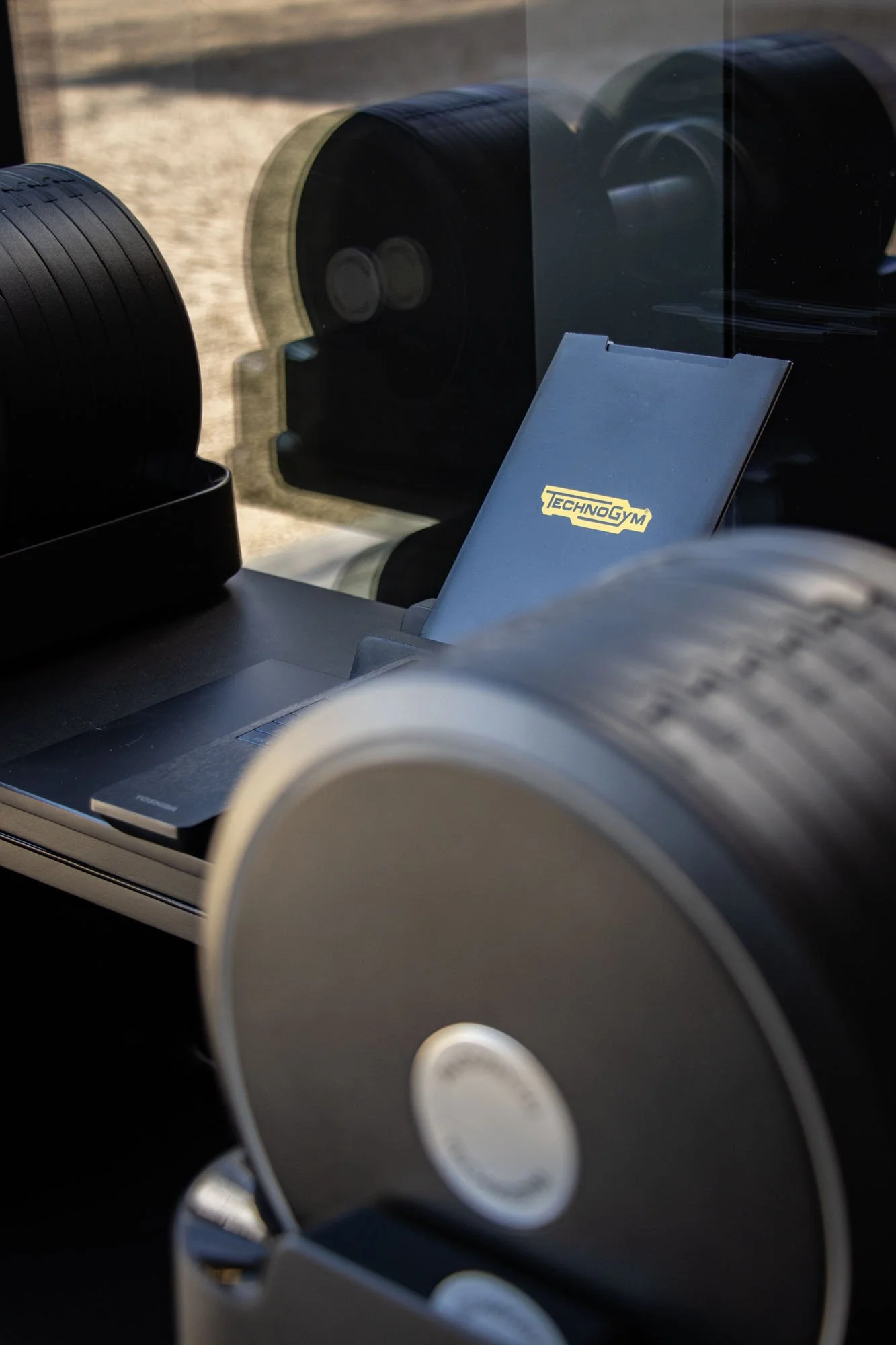 Zwarte Technogym-dumbbells in een rek in een thuisgym met daglicht
