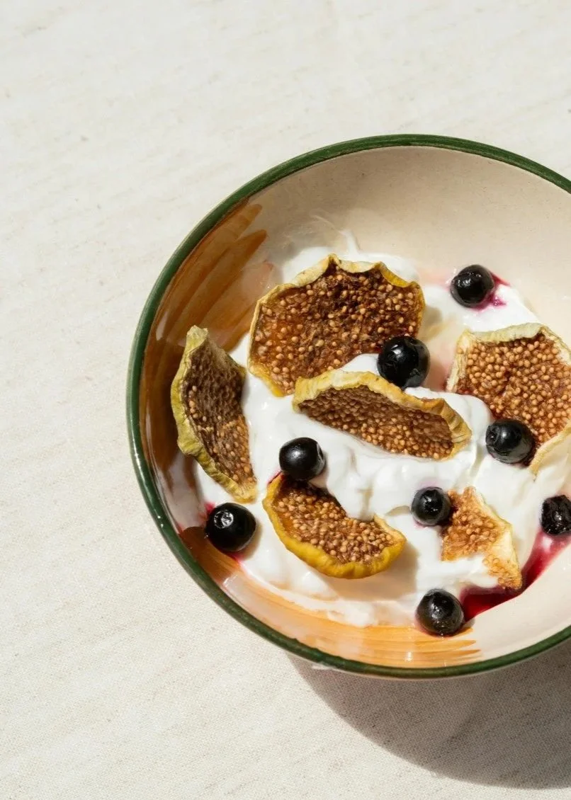 Bol rempli de yaourt nature, décoré avec des tranches de figues et des bleuets.